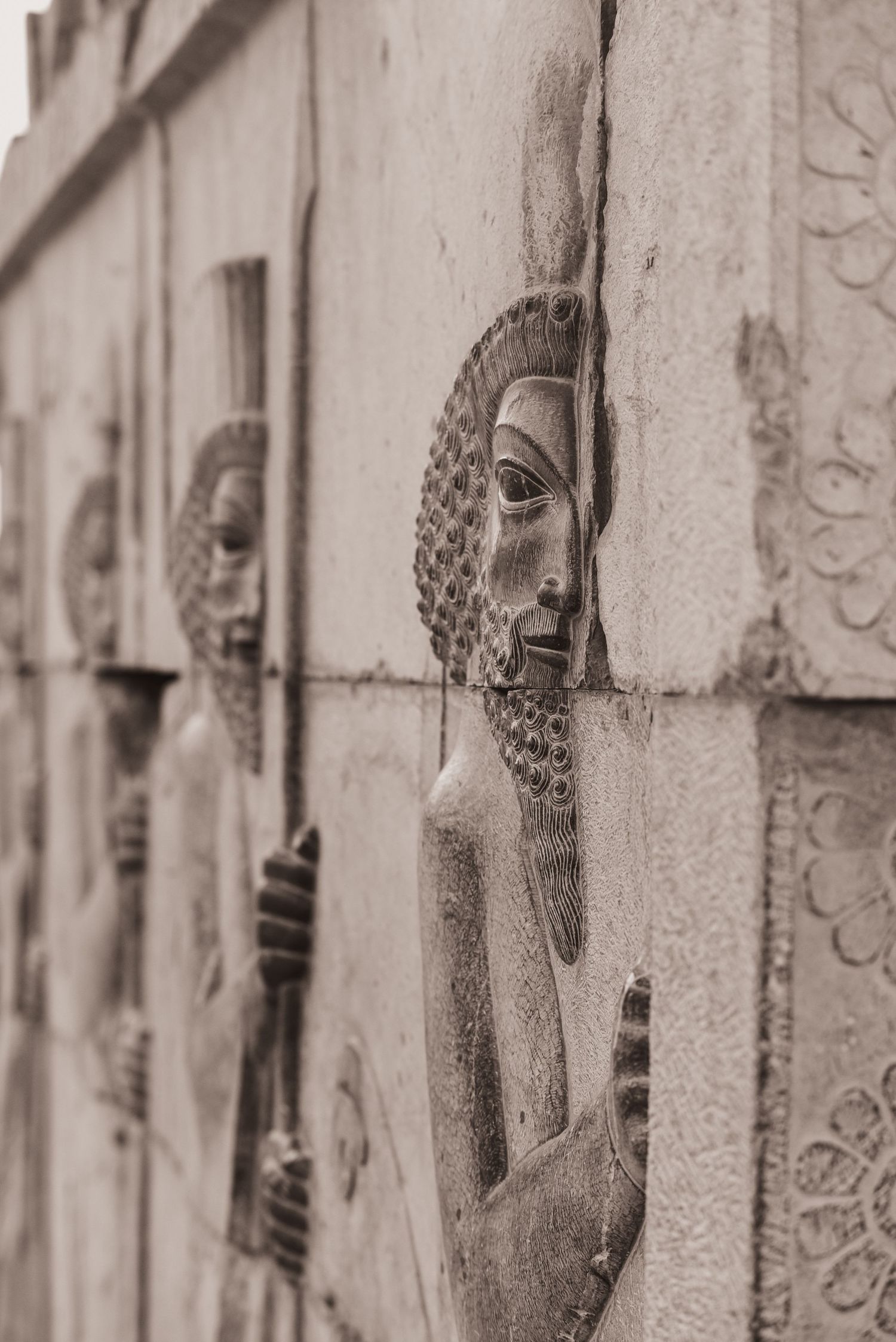 Stone relief carving showing detailed profile figures with beards and ornate details.