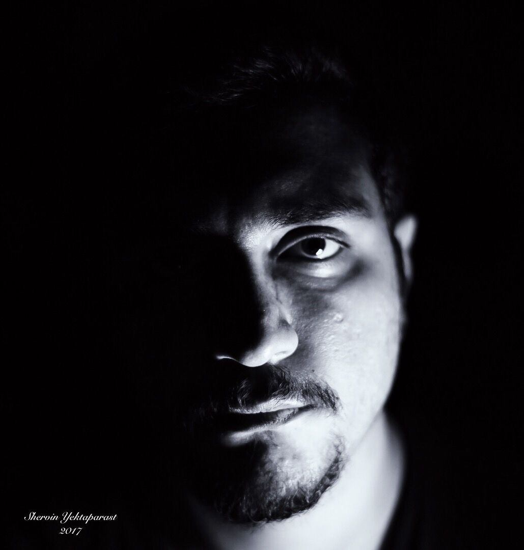 Dramatic low-key portrait showing half a face emerging from darkness.