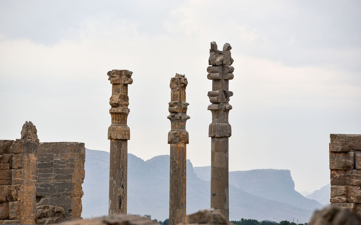 Ancient stone columns stand against mountain landscape at historic Persepolis ruins.