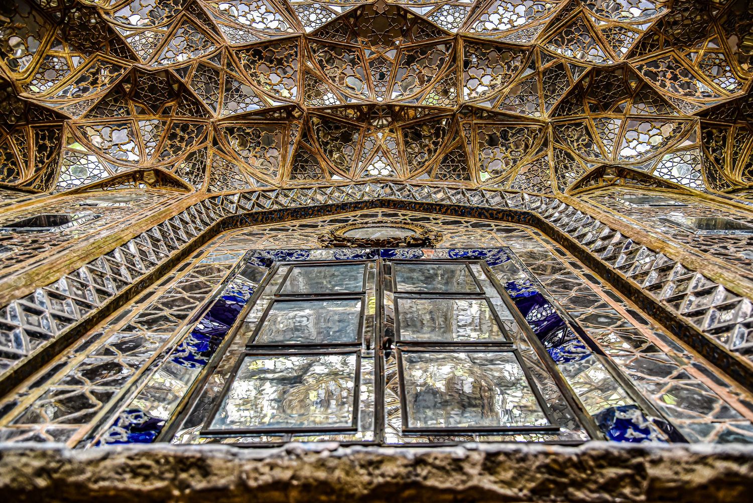 Ornate geometric Islamic ceiling patterns with blue accents and intricate muqarnas architectural details.