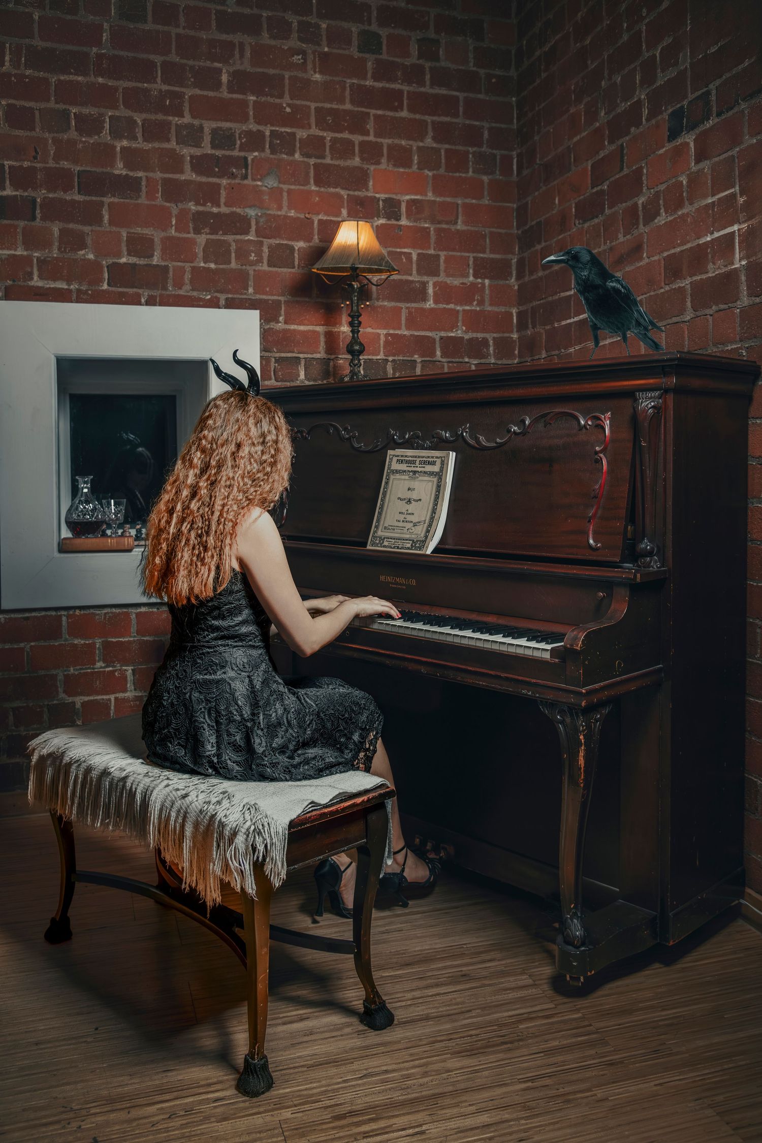 Moody scene with piano player in black dress against exposed brick wall with decorative blue bird.