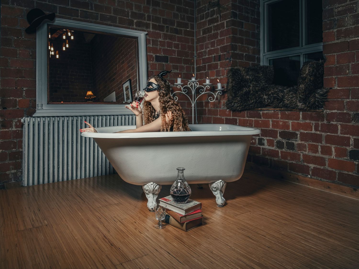 Classic clawfoot bathtub in brick room with candelabra and vintage decor.