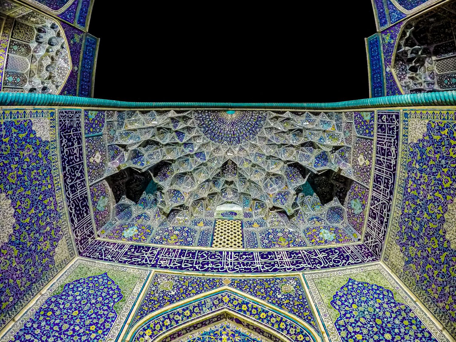 Mesmerizing blue and gold mosque ceiling with elaborate geometric patterns and stalactite vaulting.