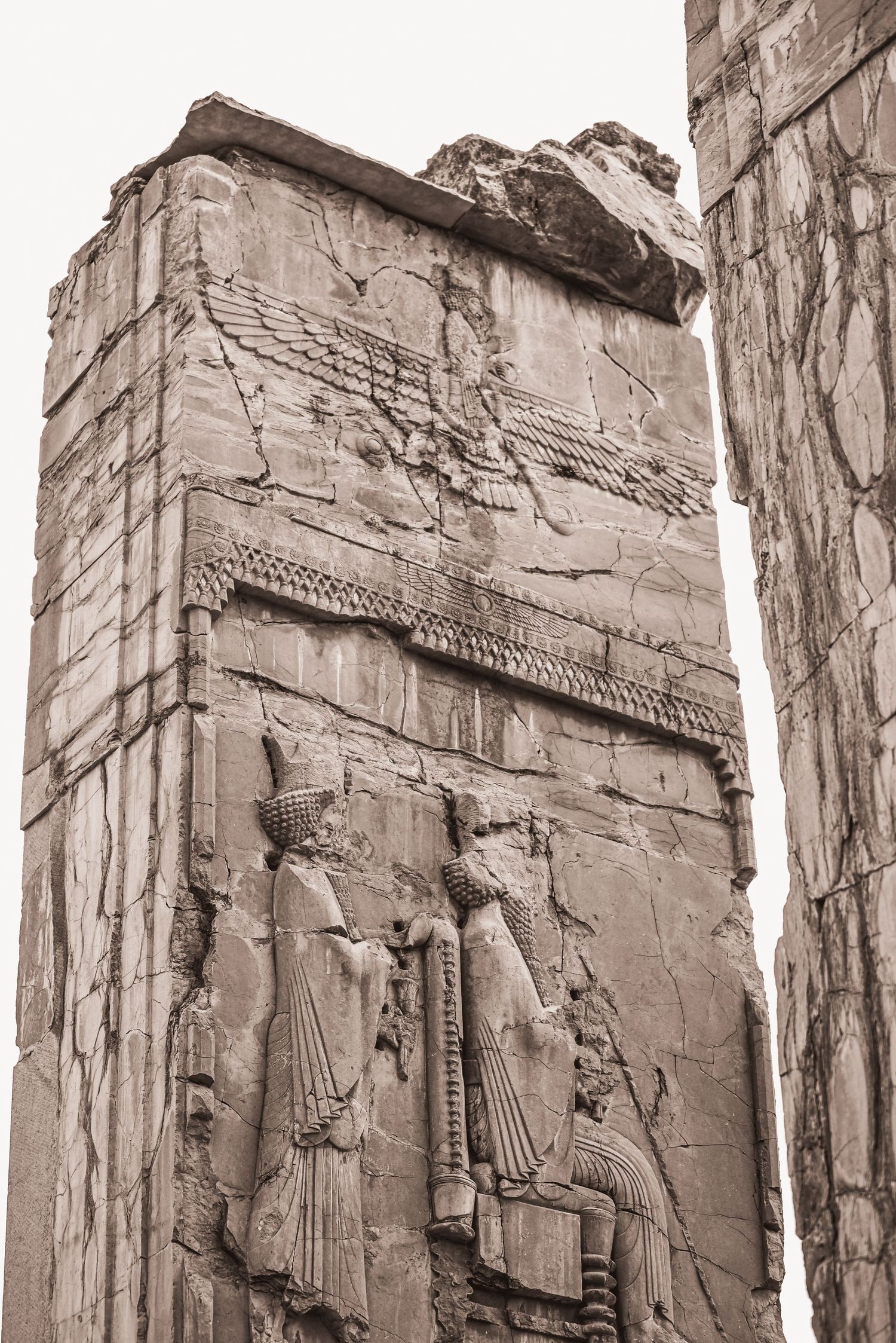 Ancient Persian relief carving showing figures in ornate robes on a stone wall at Persepolis.