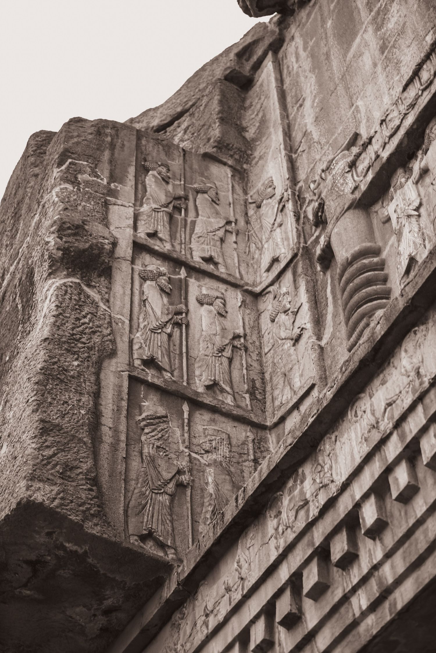 Detailed bas-relief carvings on stone walls showing ancient Persian figures in multiple panels.