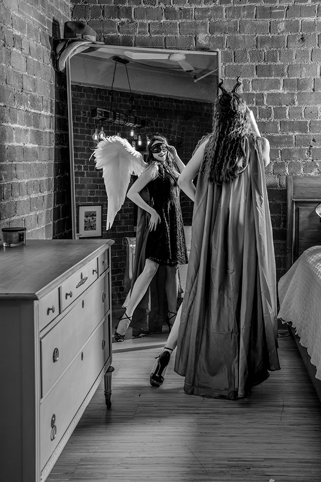 Dramatic black and white photo showing reflection in mirror with angel wings and flowing cape.