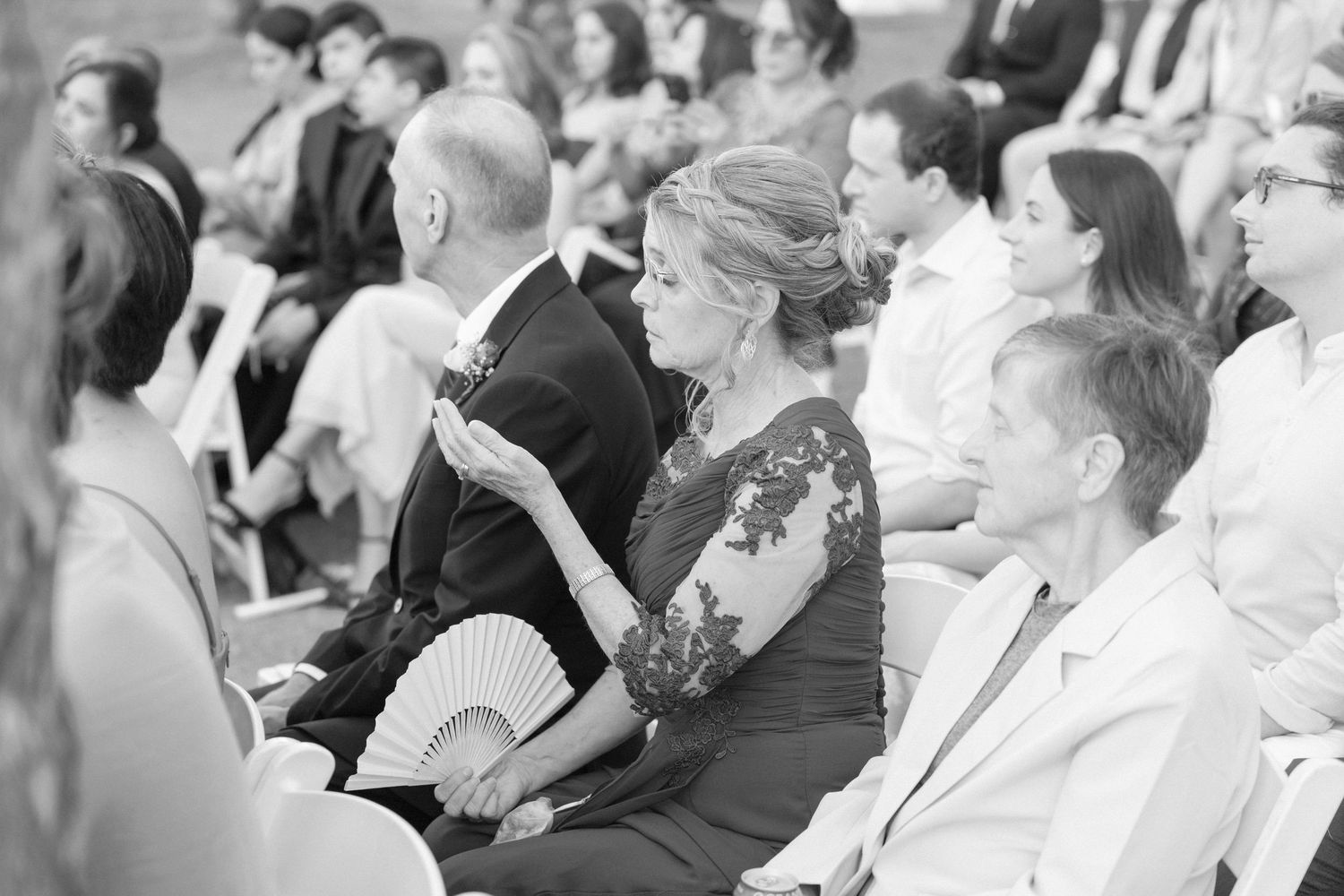 Black and white photo of wedding guests seated during outdoor ceremony.