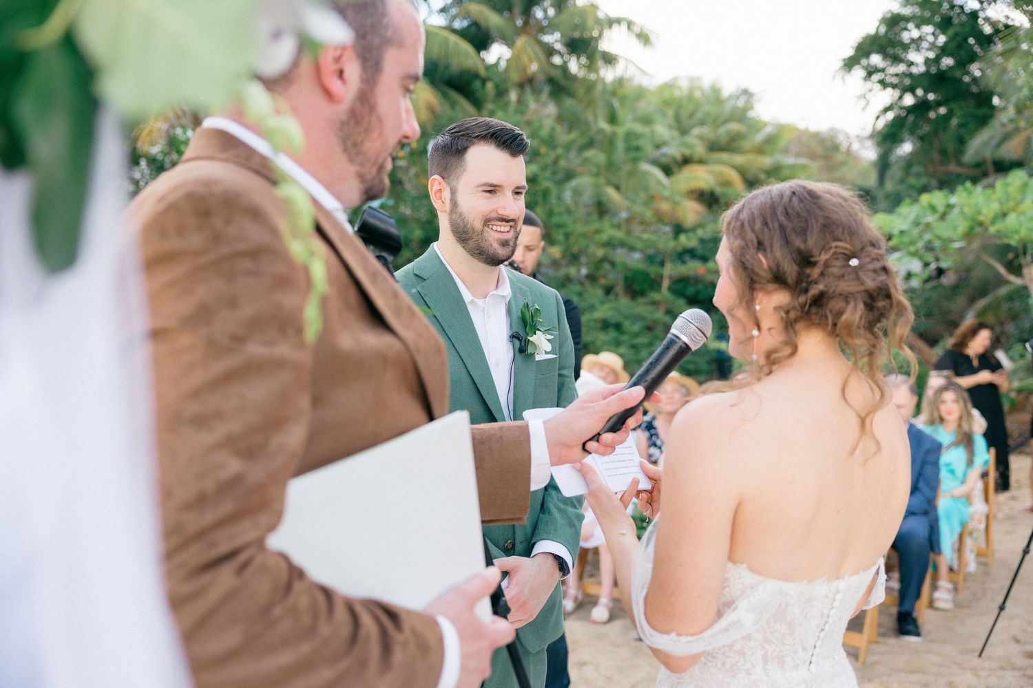 Outdoor garden wedding reception with guests mingling among green foliage.