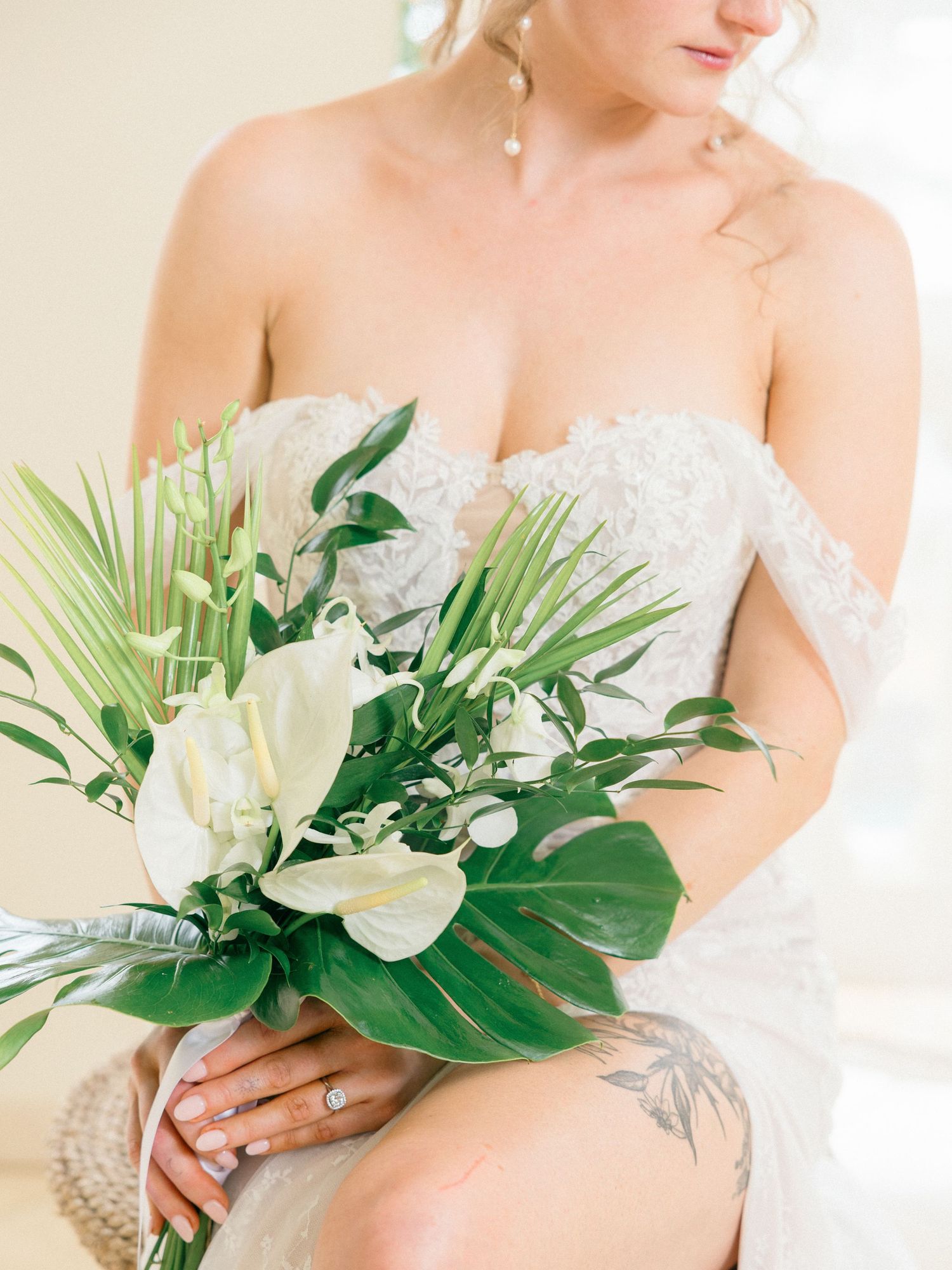 Elegant tropical wedding bouquet with white flowers and monstera leaves.