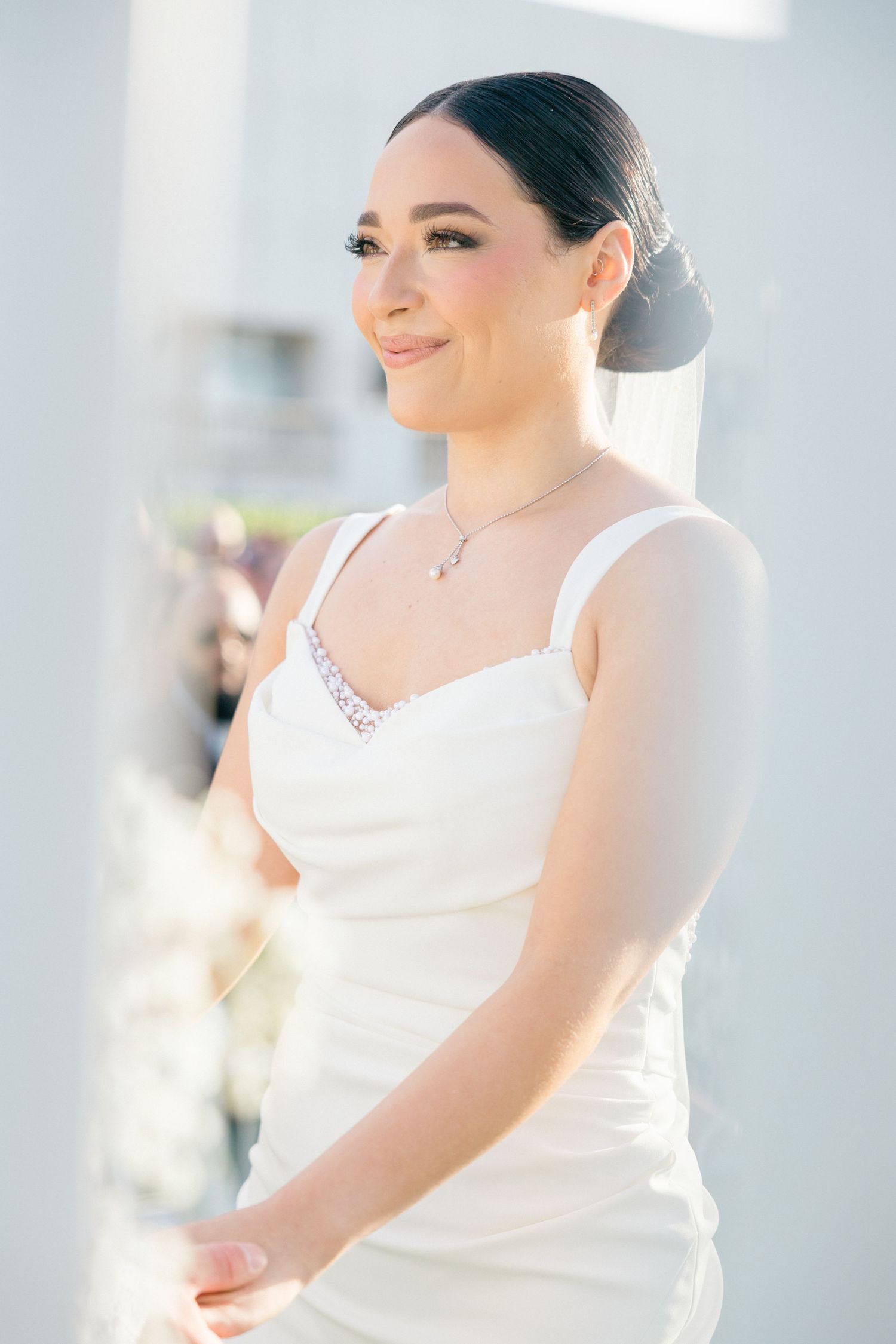 Close-up portrait of person in white wedding dress against light blue background.