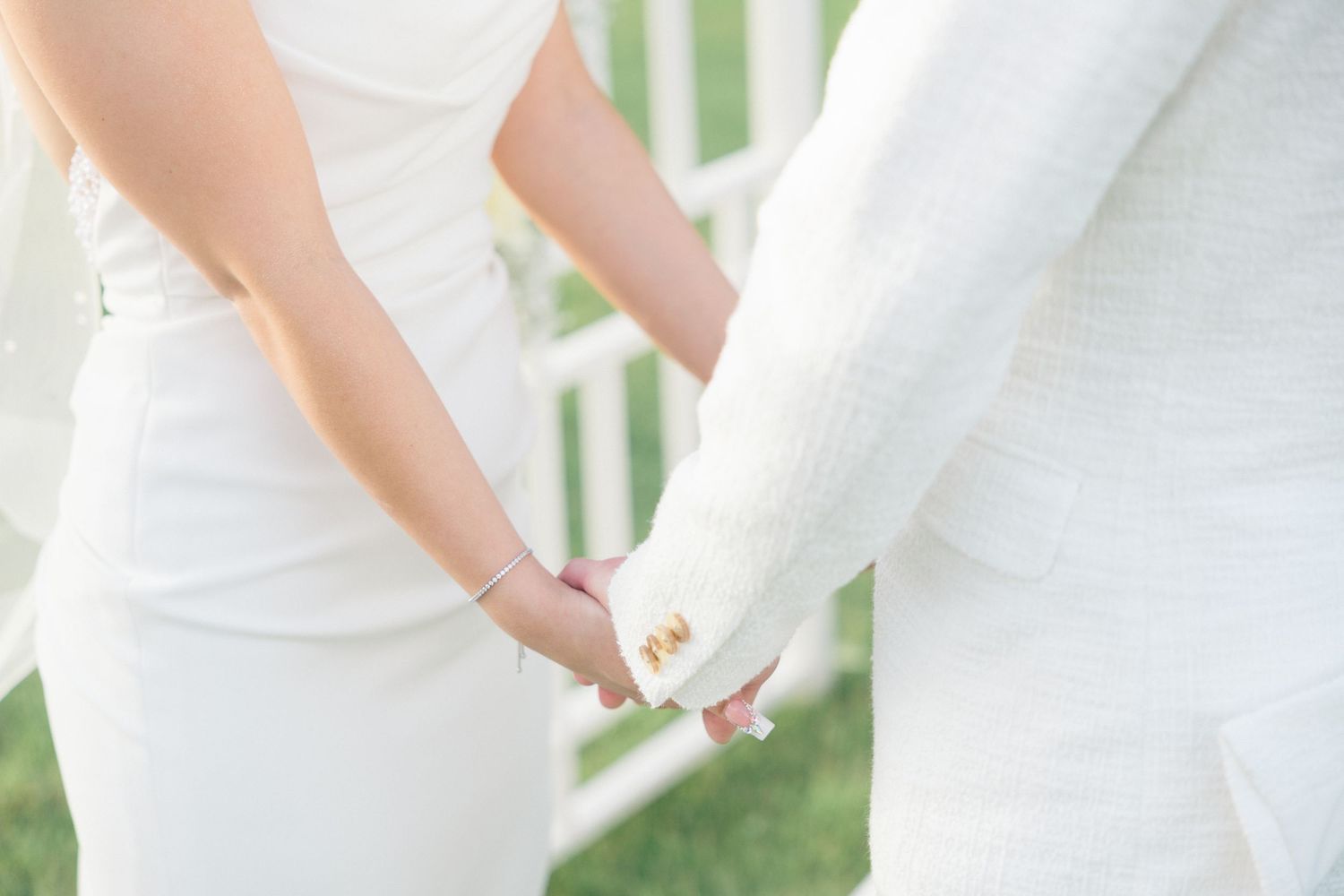 Detail shot of white wedding dresses during outdoor ceremony.
