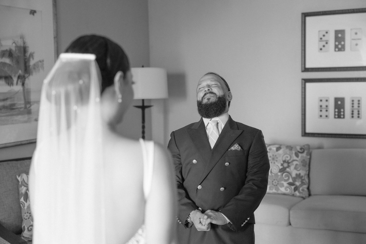 A candid black and white first look moment between a bride and groom in a hotel suite.