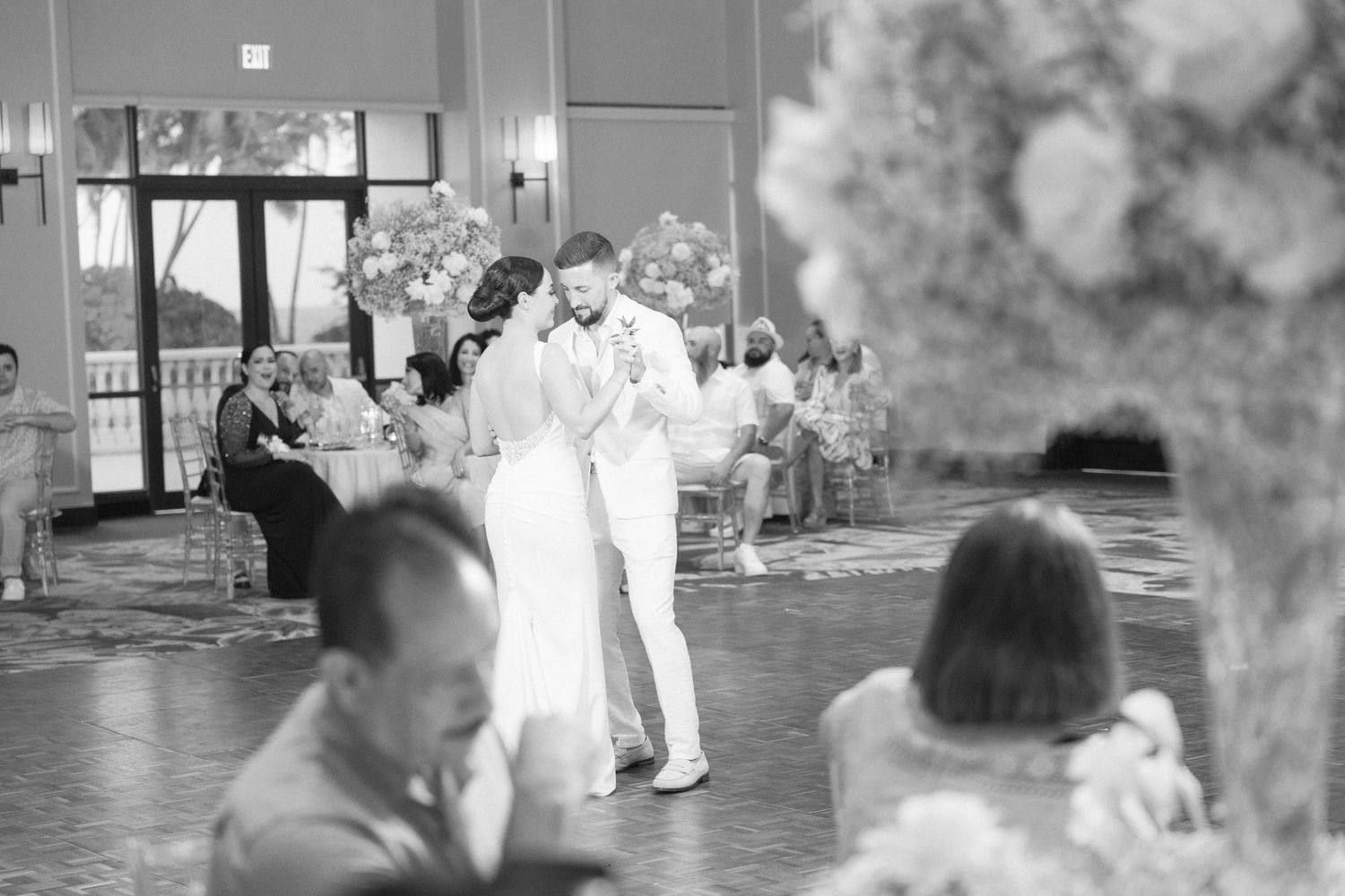 Black and white photo of couples dancing in an elegant ballroom setting at a wedding reception.