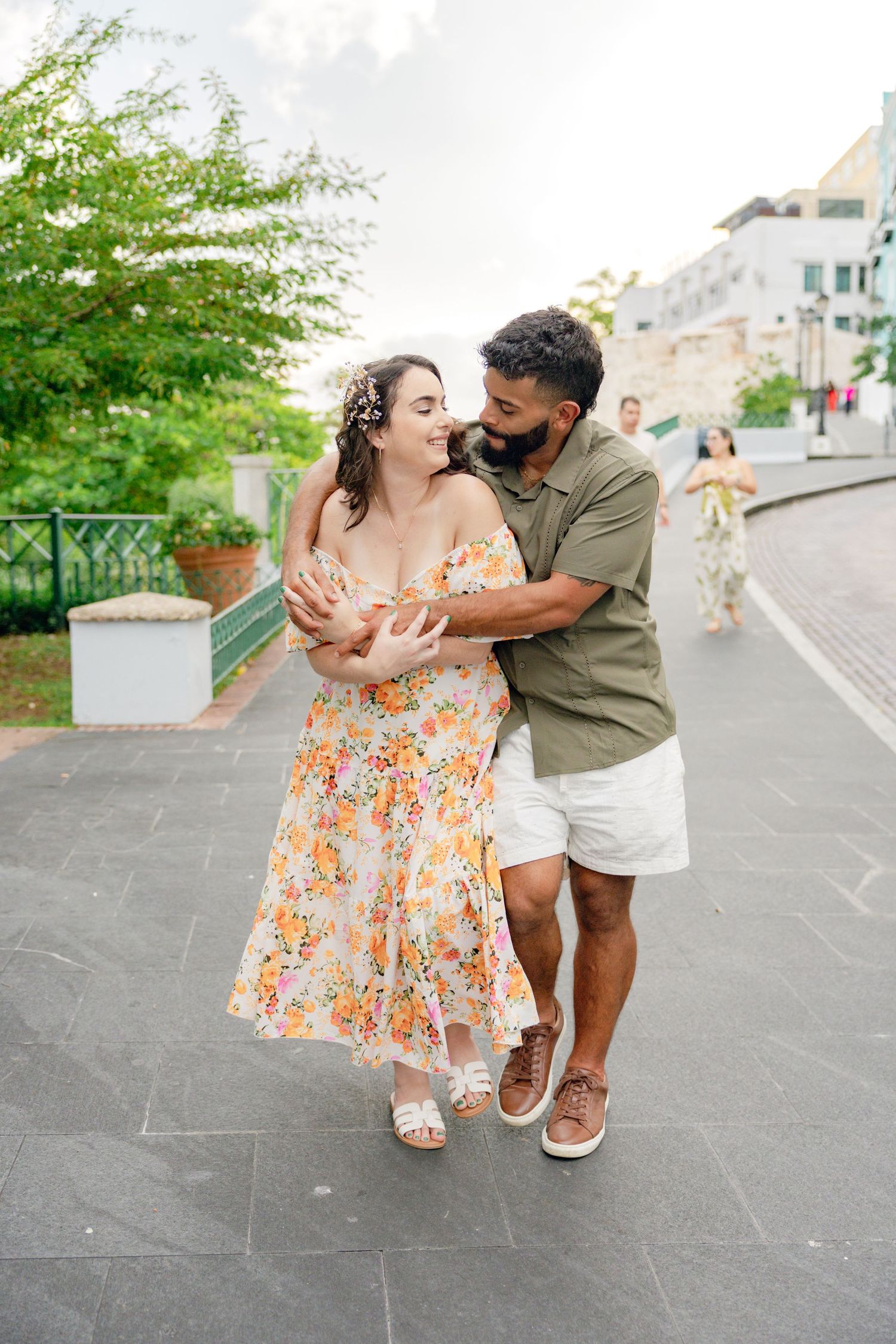 Playful engagement photos of a couple dancing and laughing on a stone pathway.