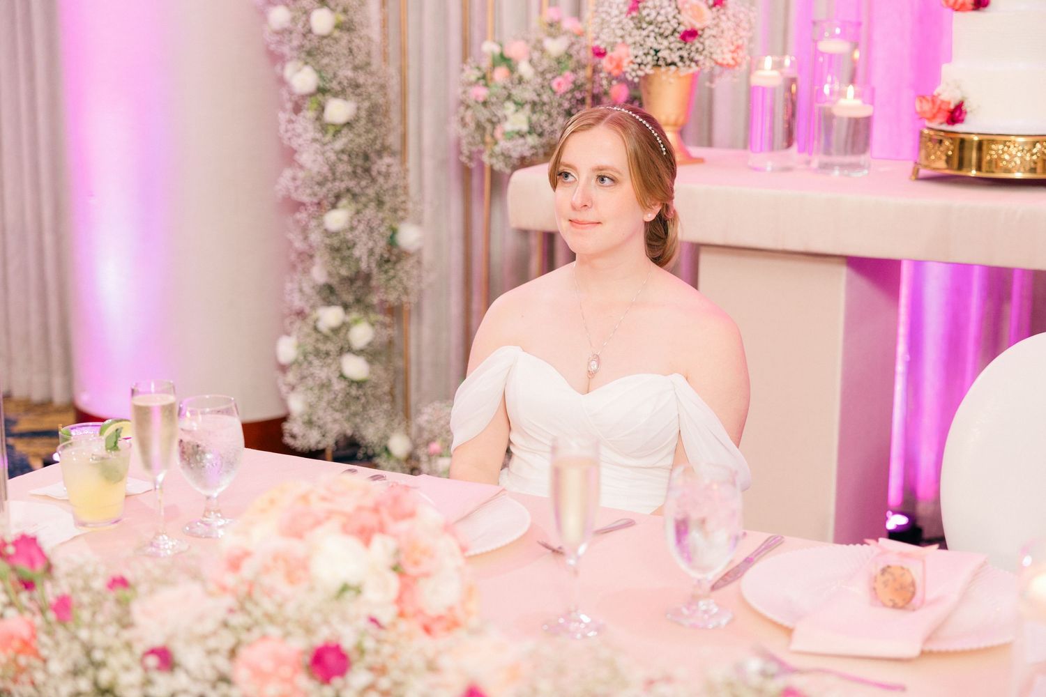 Elegant wedding reception table setting with pink floral arrangements and soft lighting.