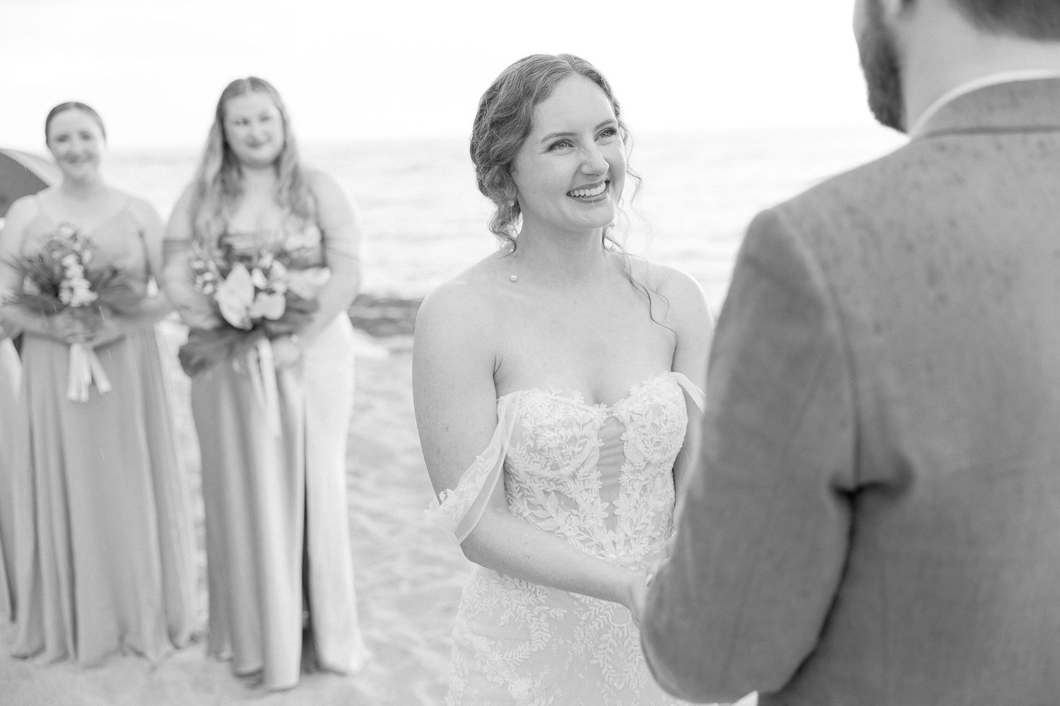 Wedding party members stand on a beach during the ceremony.