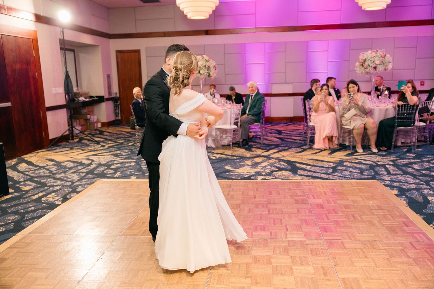 Wedding reception venue decorated with purple uplighting and geometric patterned flooring.