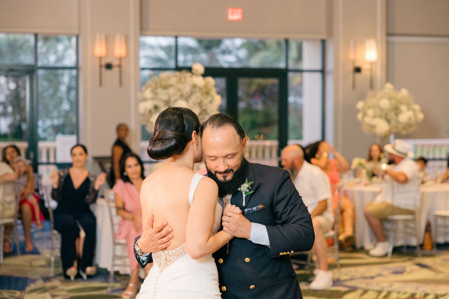 Wedding celebration features couples dancing together in an elegant ballroom with decorative lighting.