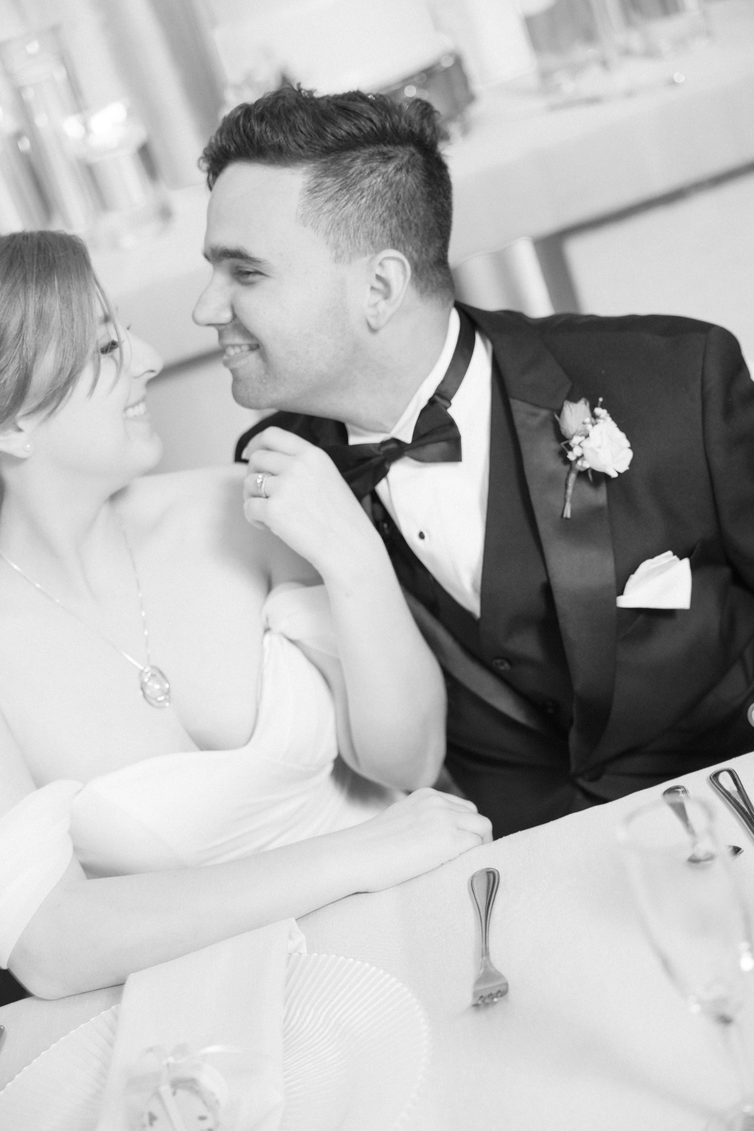 An intimate black and white wedding photo showing a tender moment at the reception.