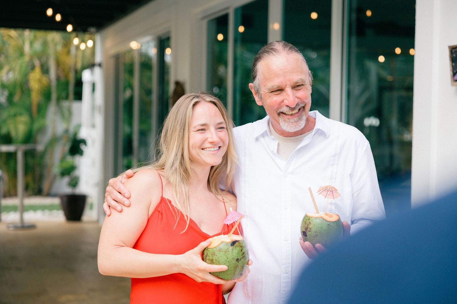 A couple smiling while holding coconut drinks at an outdoor venue.