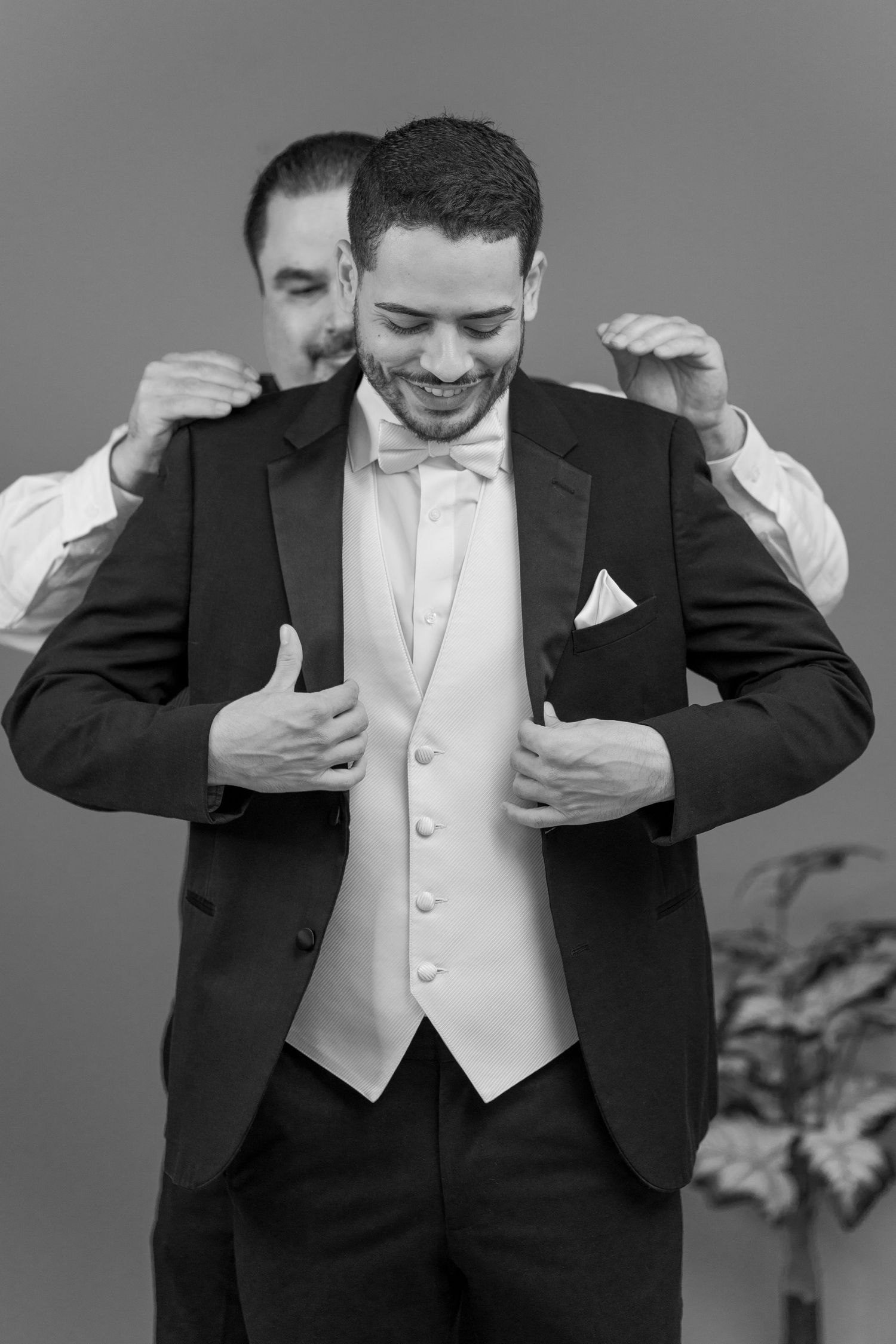 Black and white sequence of groom adjusting his formal wear with animated expressions.