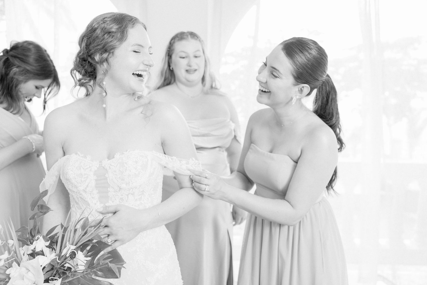 Joyful wedding party celebrating in light-filled room.