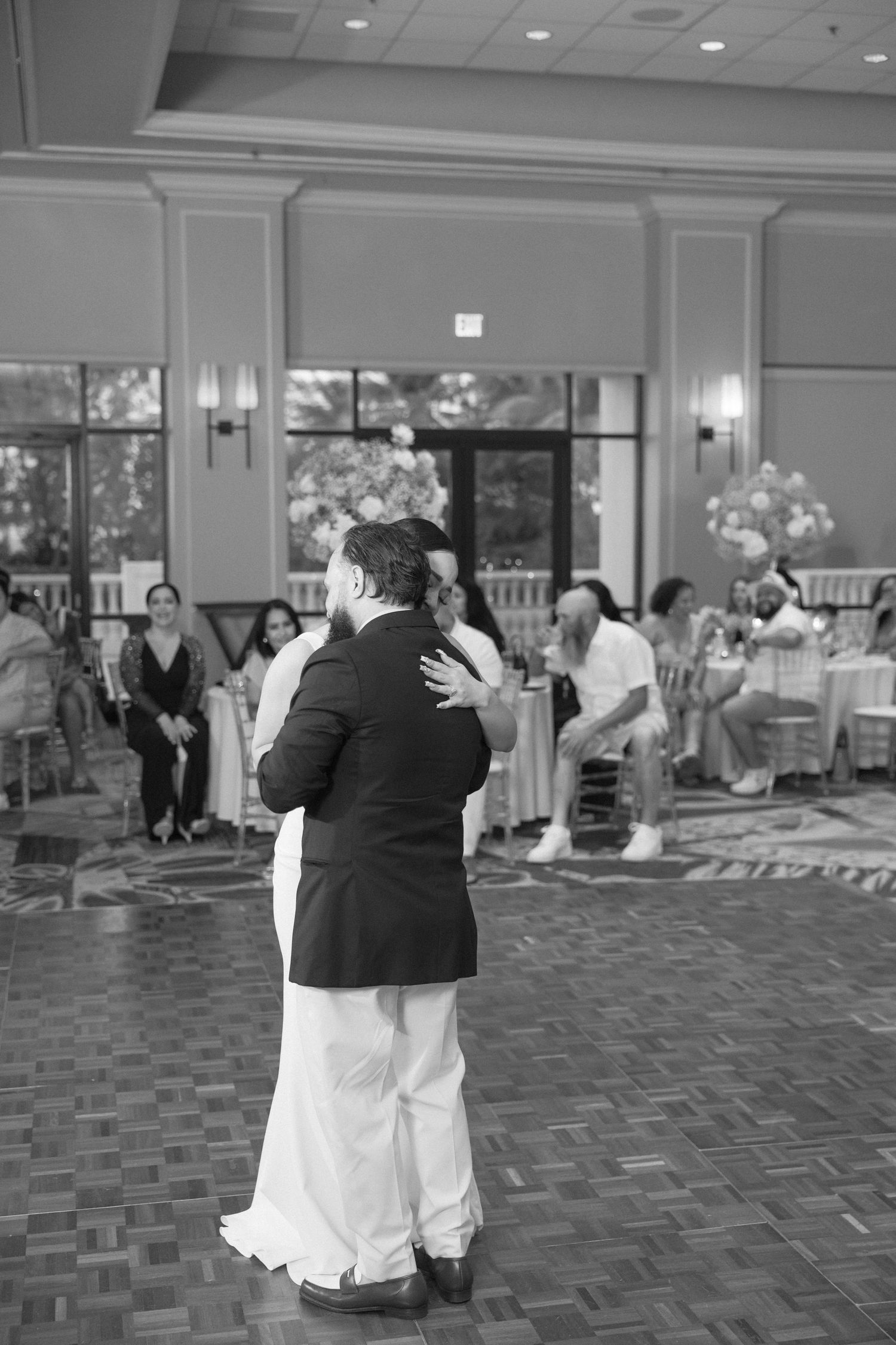Couples share romantic slow dances on a patterned dance floor at an indoor wedding venue.