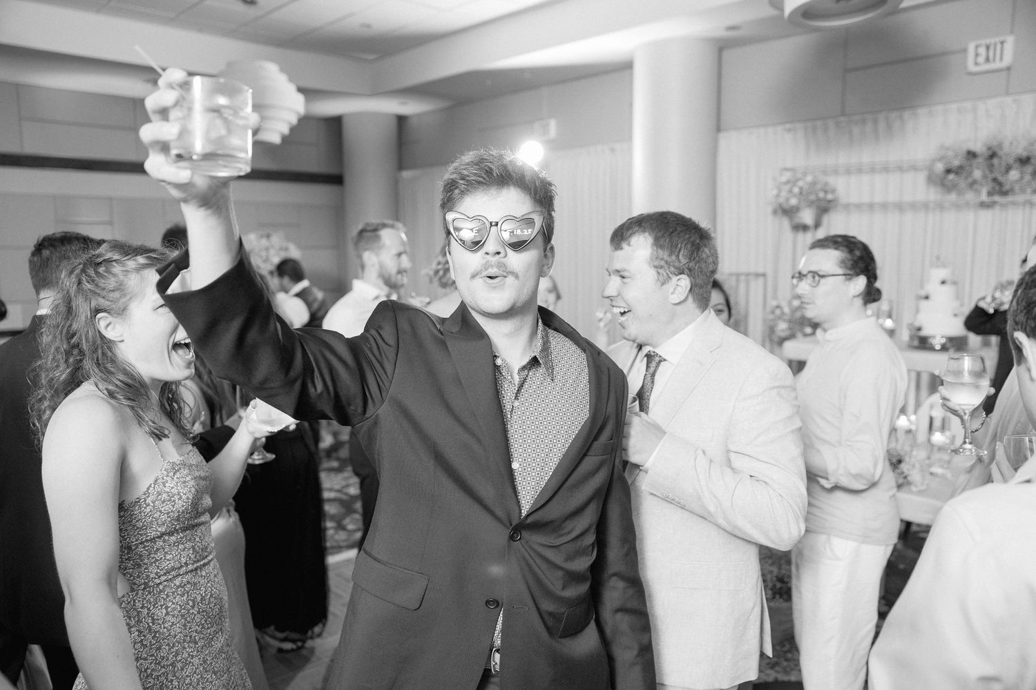 Black and white candid shot of wedding guests celebrating on the dance floor.