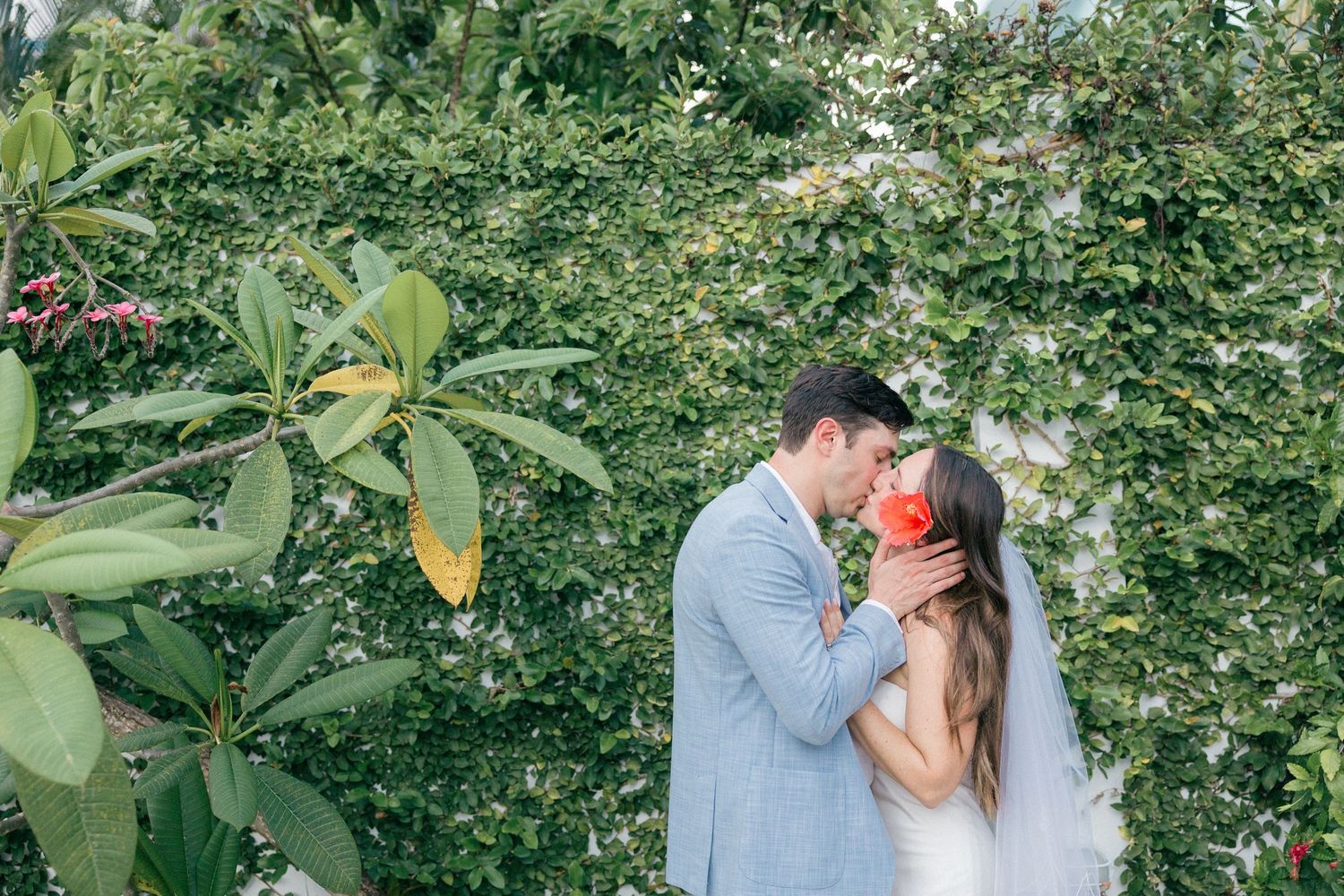 An intimate outdoor portrait session among green tropical foliage and flowering plants.