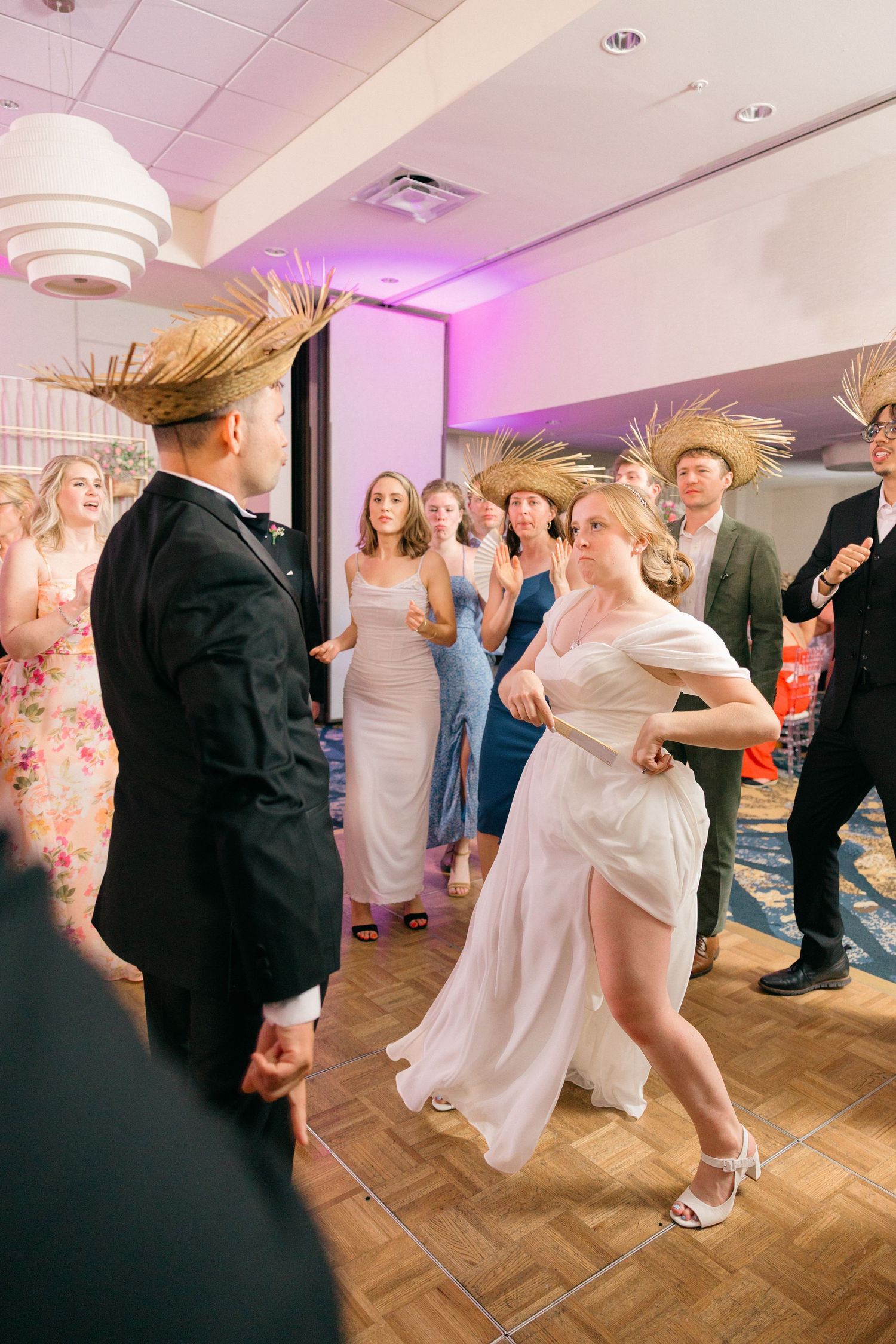 Wedding reception dance floor with pink lighting and guests dancing together.