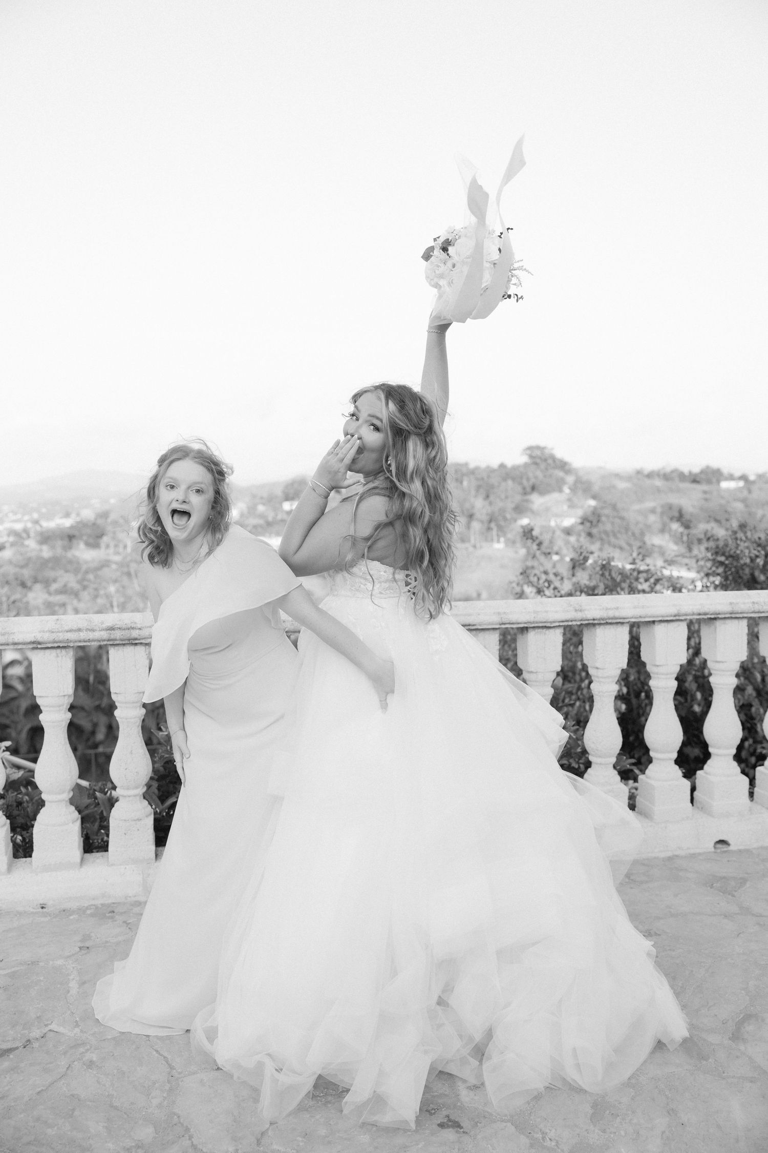 Joyful black and white photos showing a bride in a flowing dress posing on a balcony.