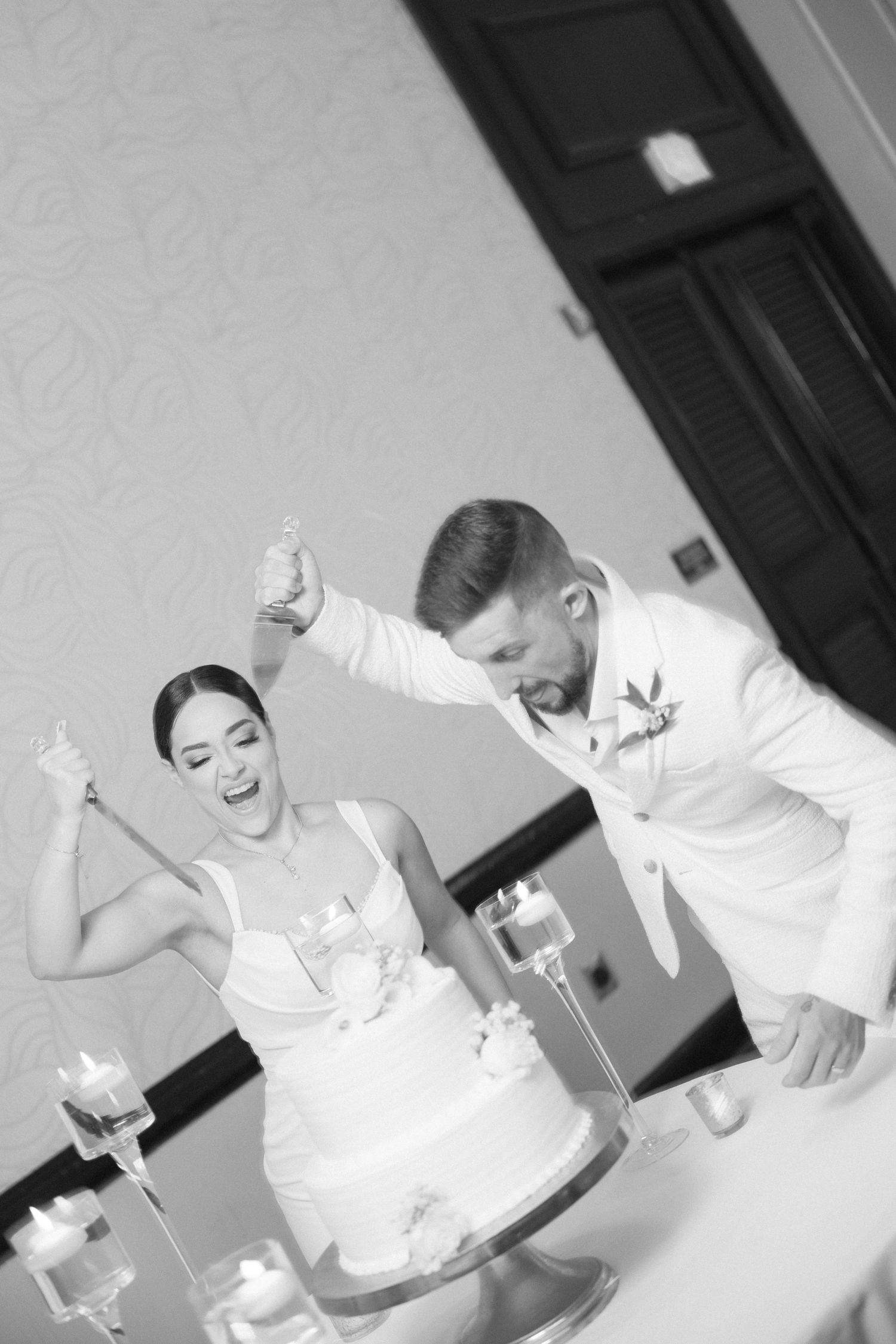 A joyful moment captured in black and white as a couple celebrates with their wedding cake.