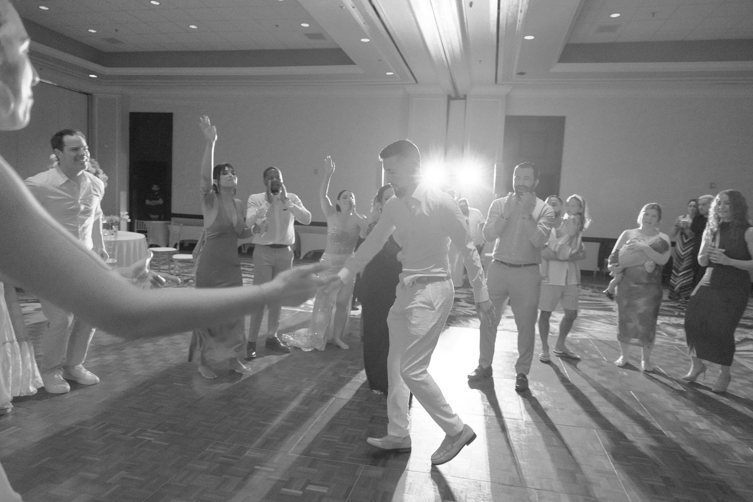Guests dancing and celebrating at an indoor wedding reception with dramatic lighting.