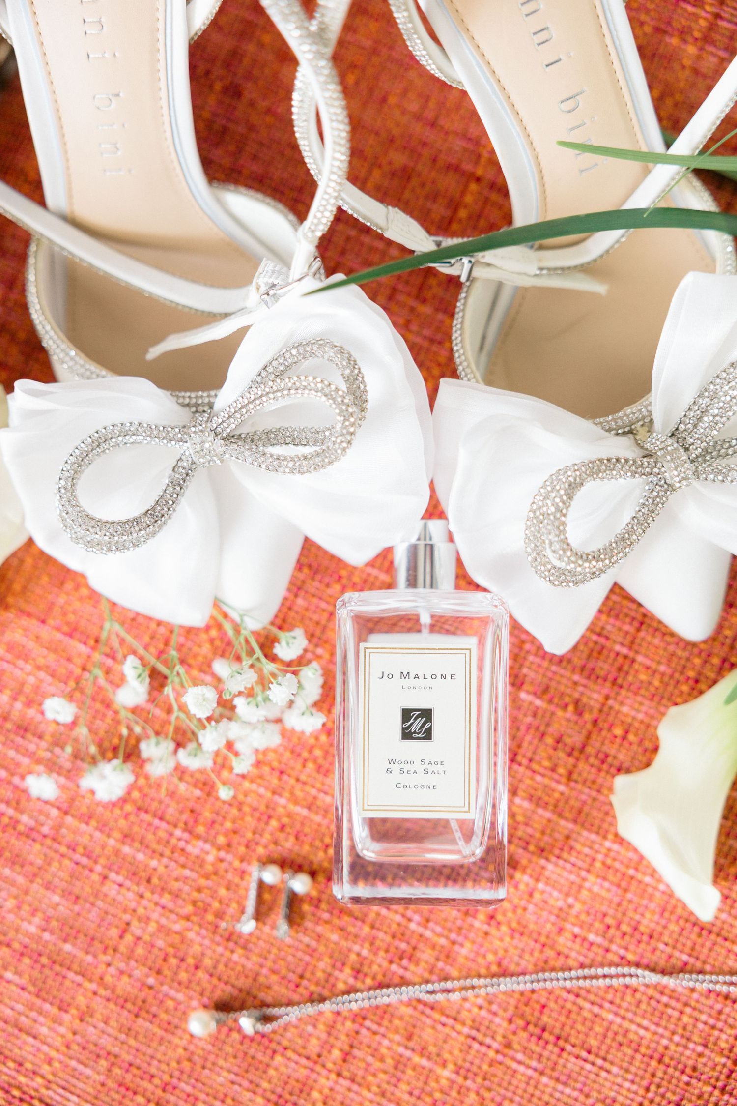 Jo Malone perfume bottles with white ribbons against coral background.