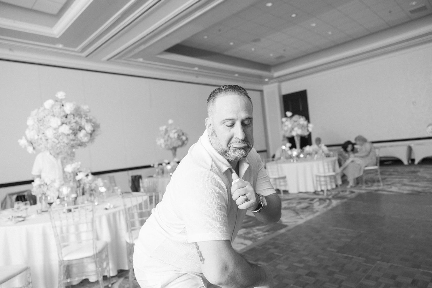People enjoying themselves at a wedding reception in an elegant ballroom with decorative lighting.