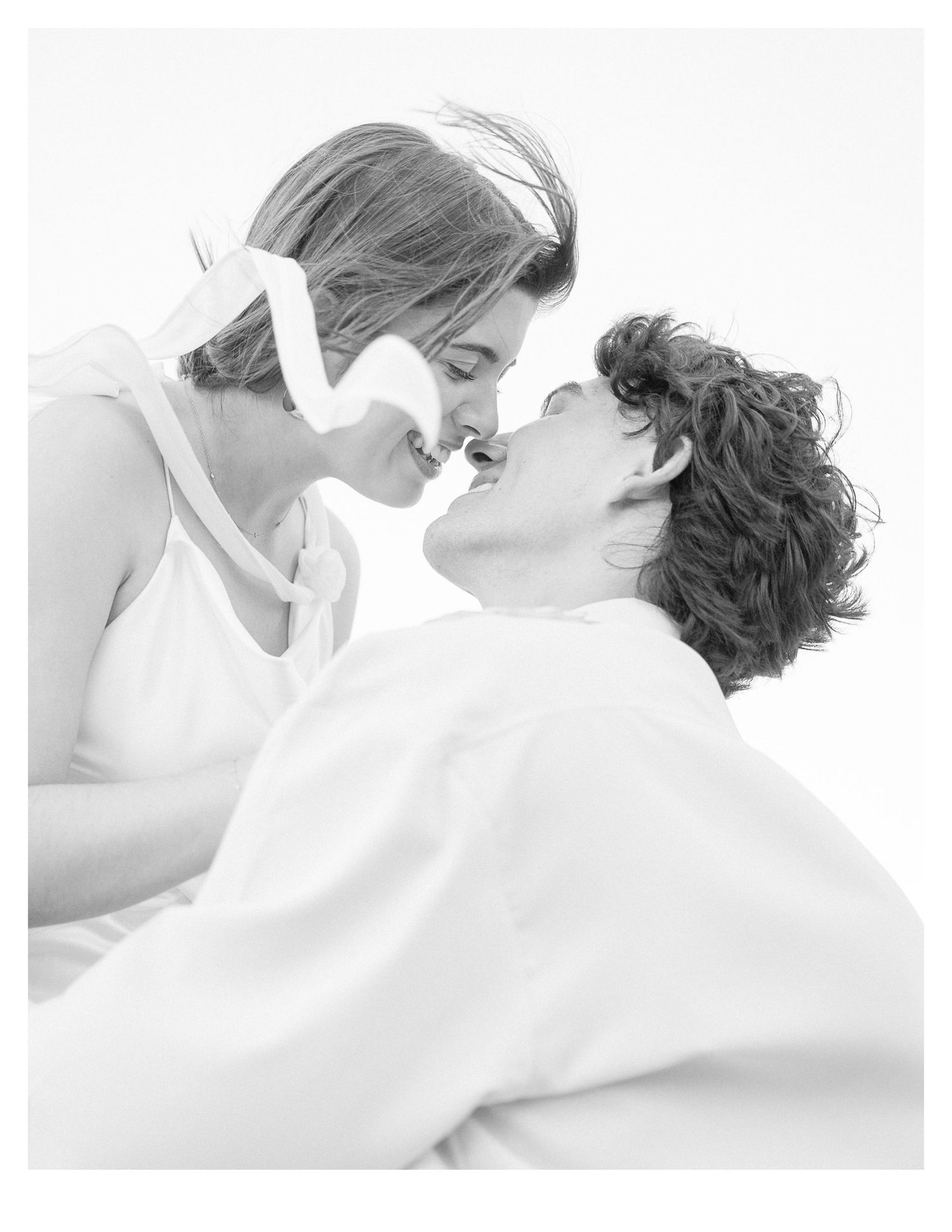 Couple in white embracing tenderly in a bright, minimalist setting.