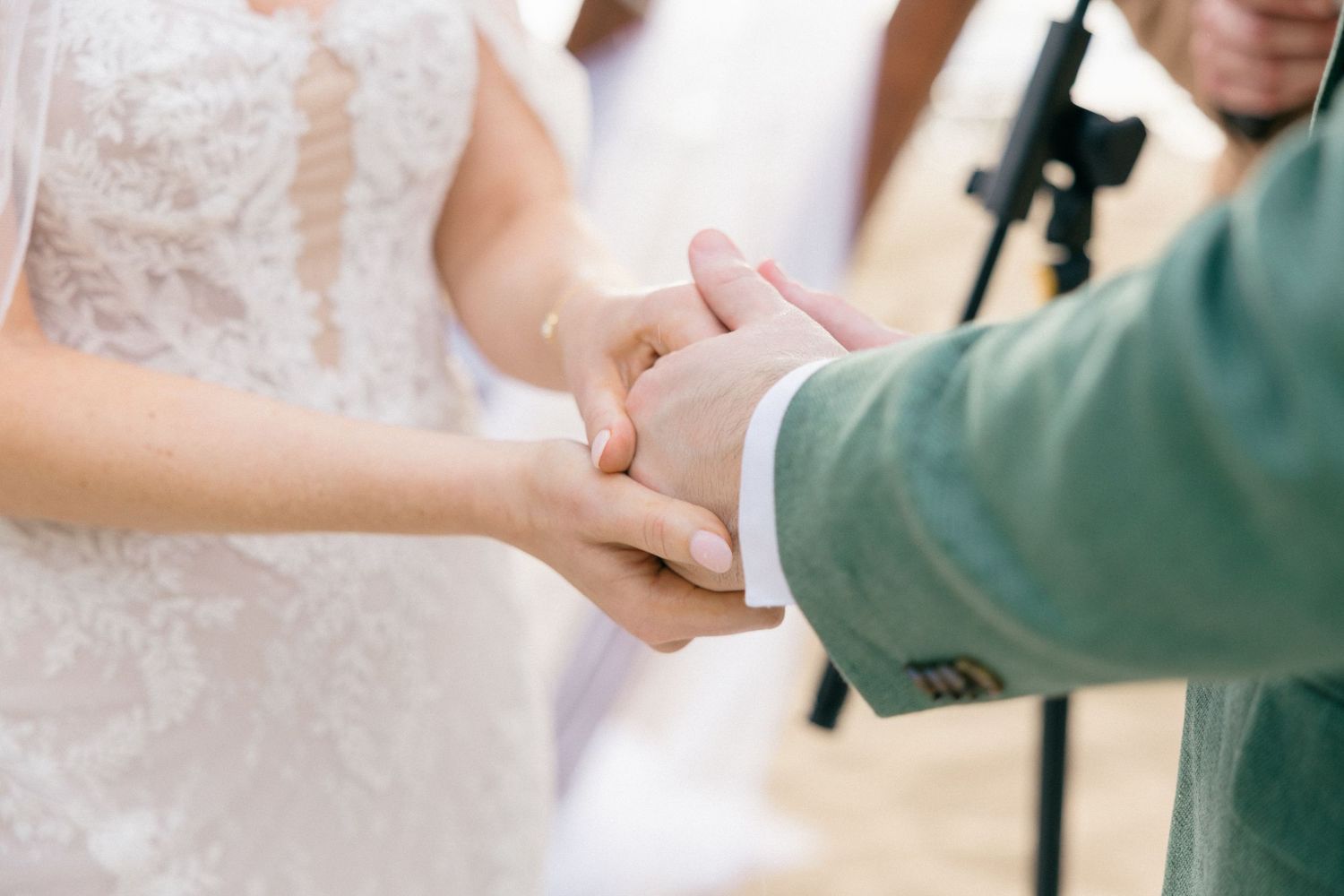 Close-up of hands exchanging rings during a beach wedding ceremony.