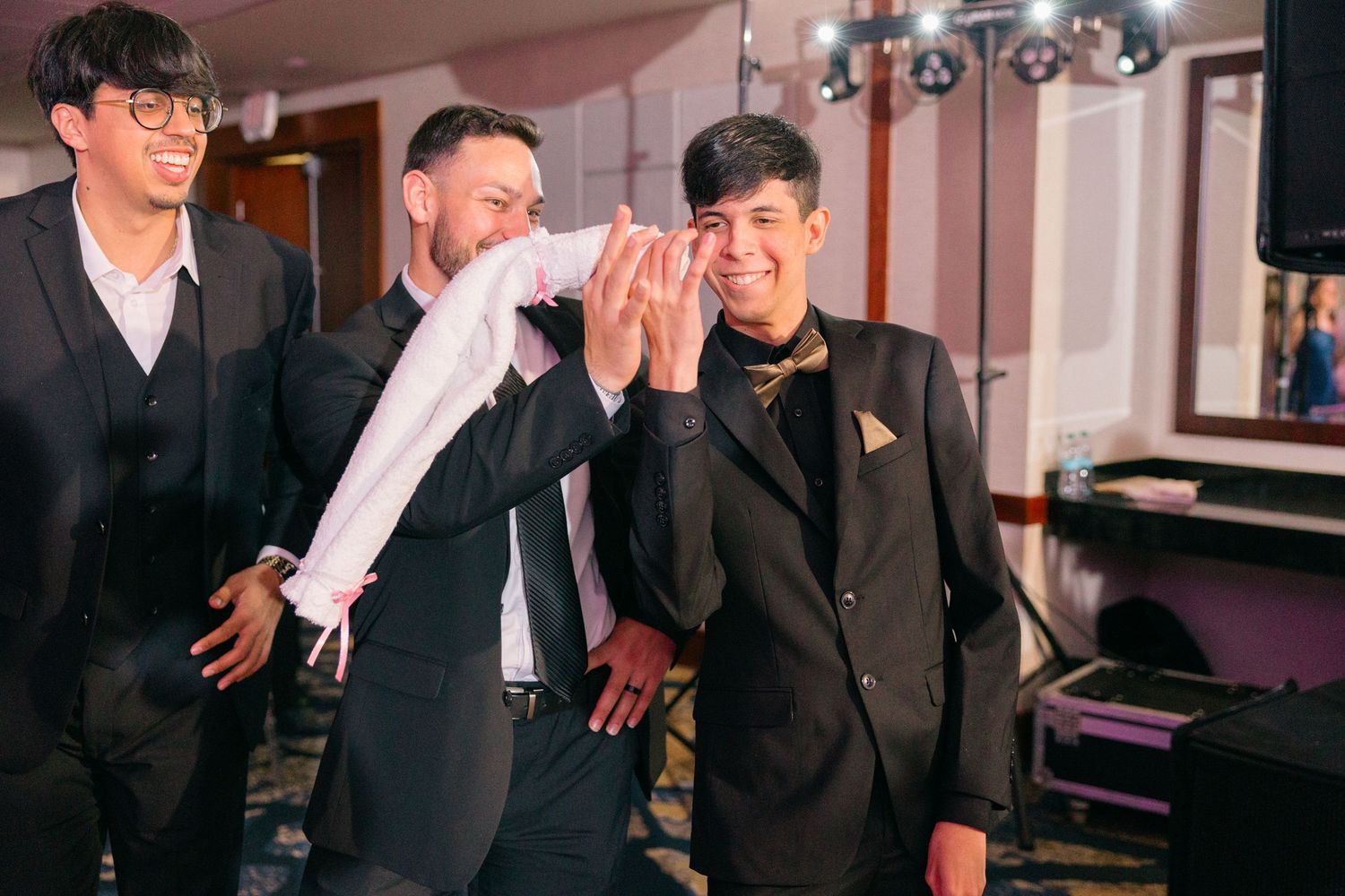 Joyful guests enjoying themselves at an indoor wedding celebration with pink lighting.