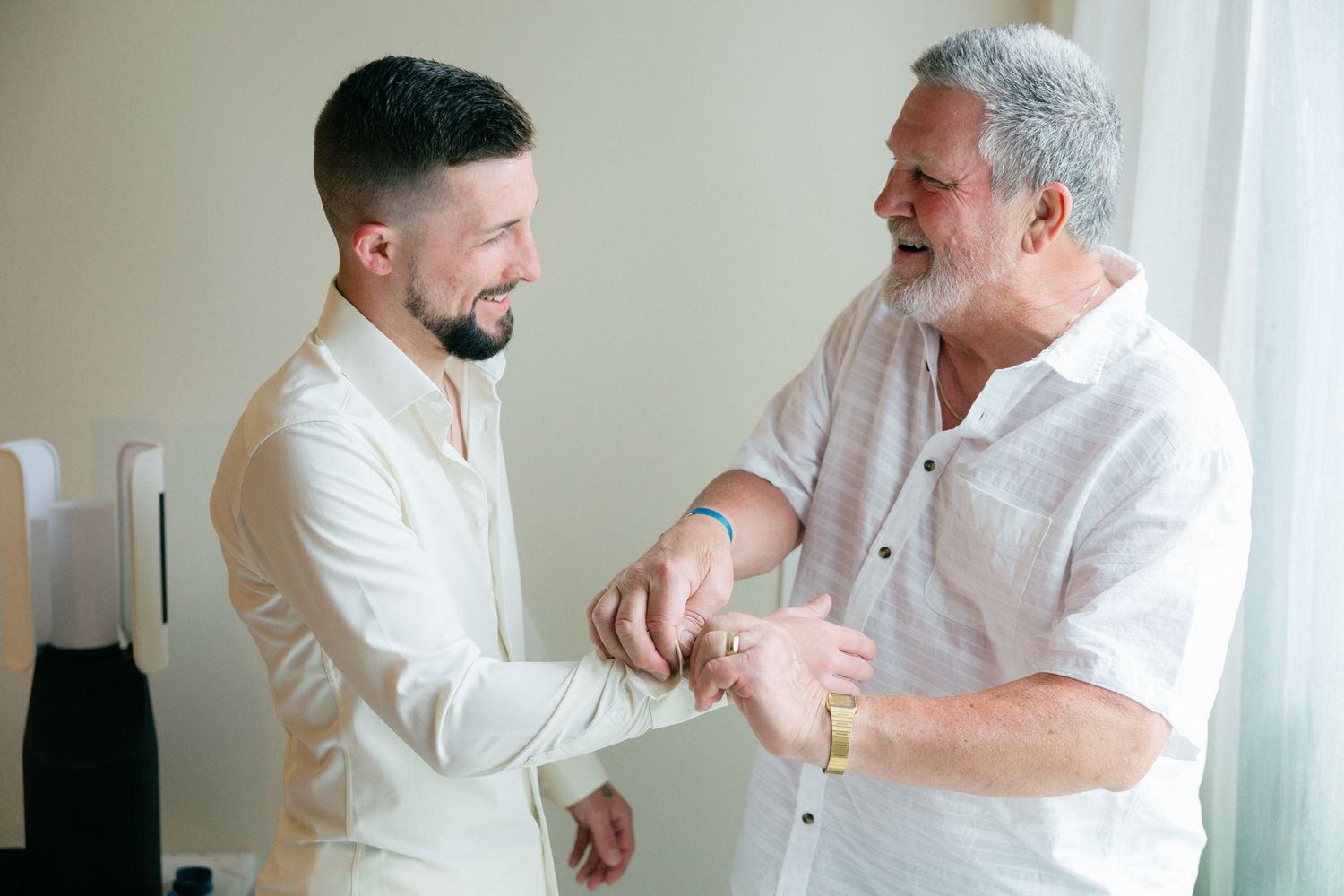 Two people in white shirts adjusting cuffs together.