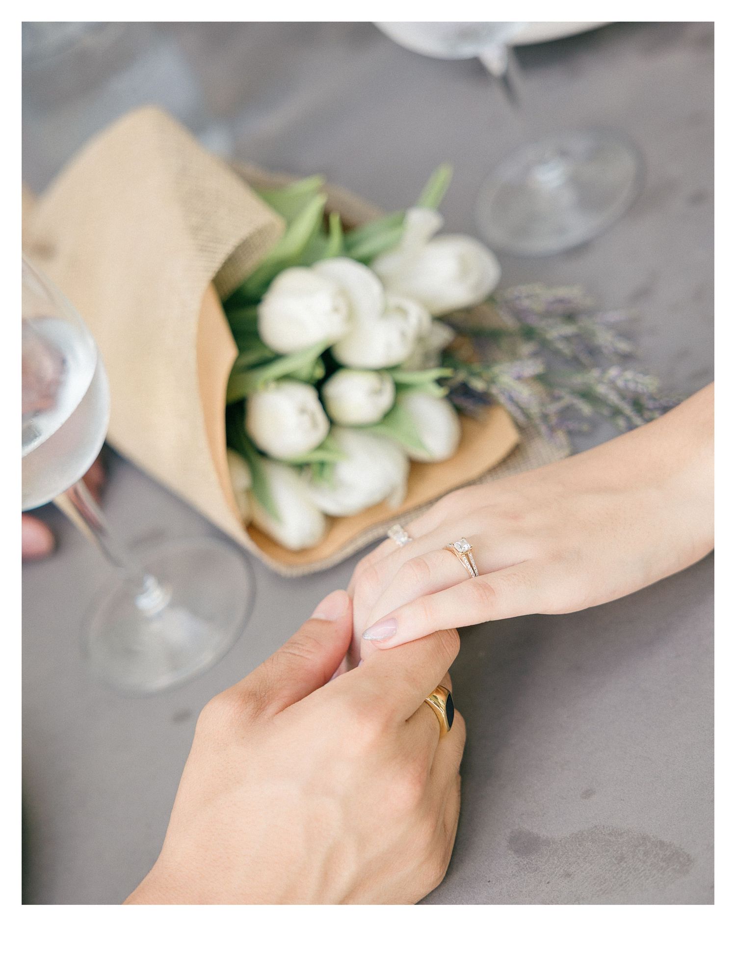 Close-up of hands arranging white flowers on a gray surface.