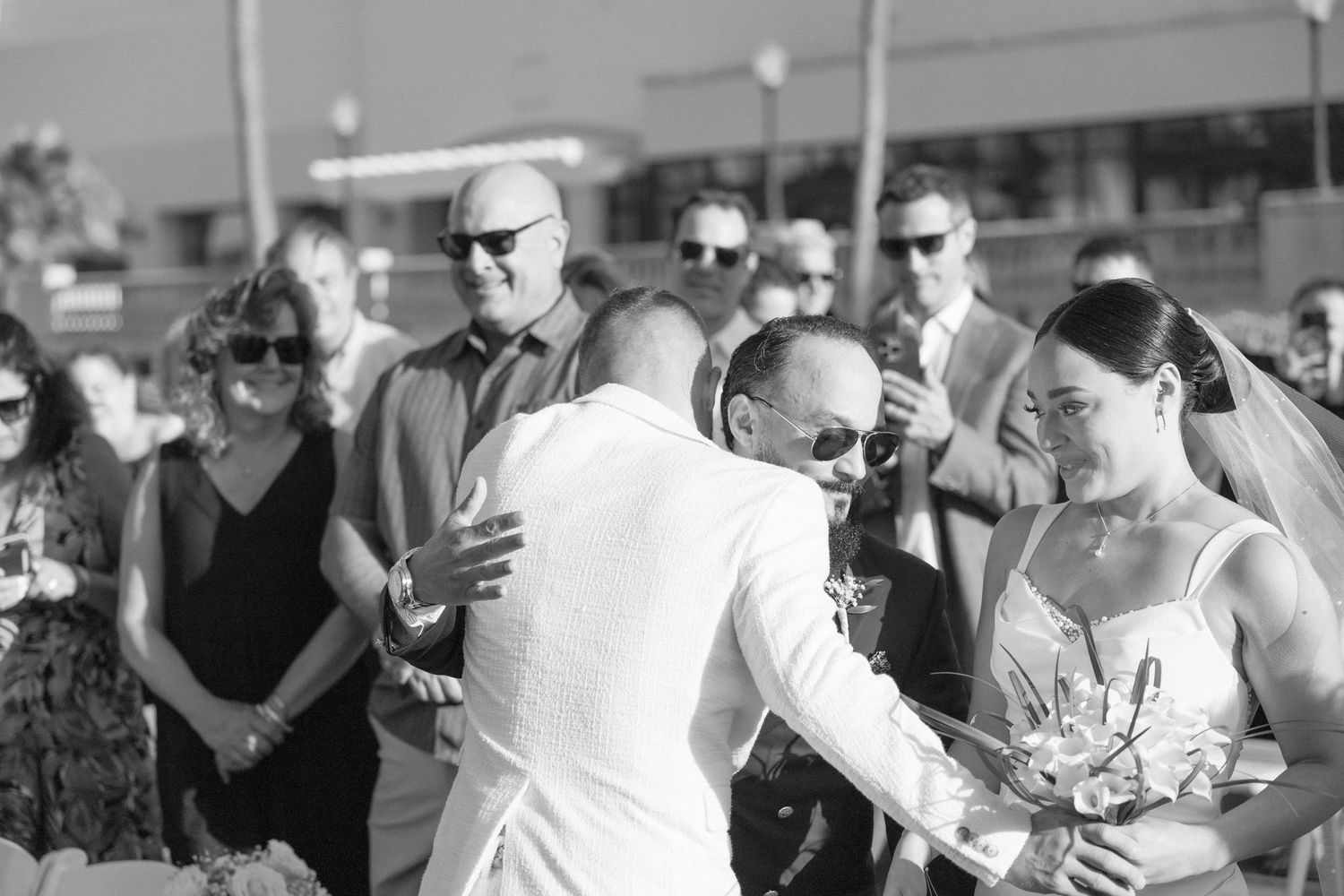 Guests capture moments on their phones during an outdoor wedding ceremony.