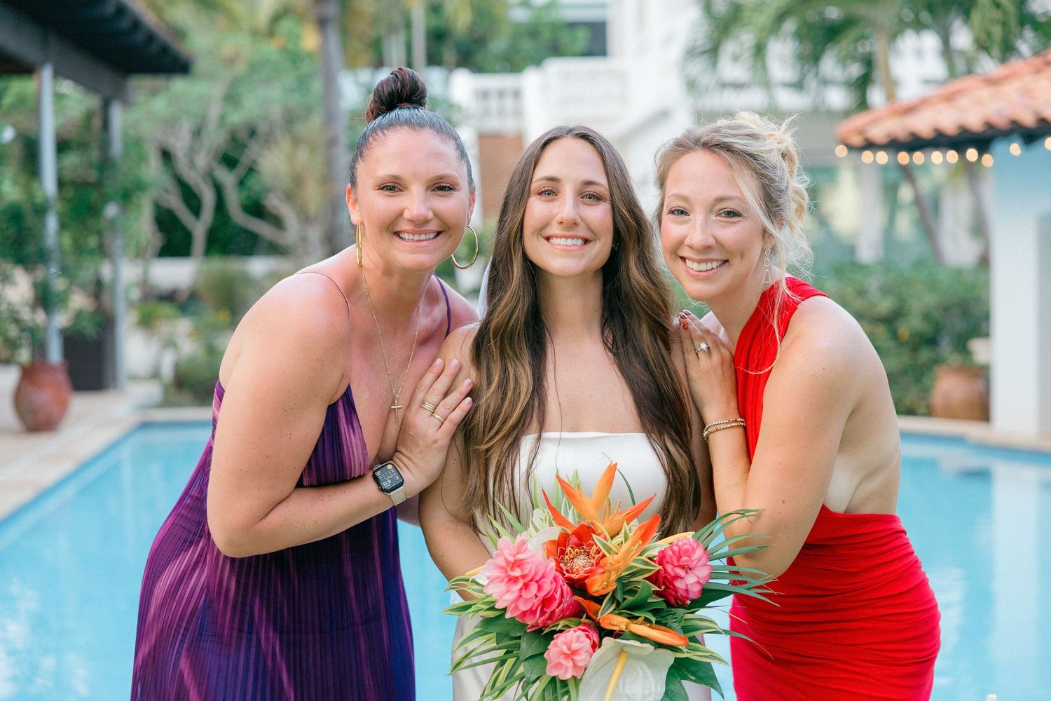 Wedding party poses for casual group shots near a resort swimming pool.