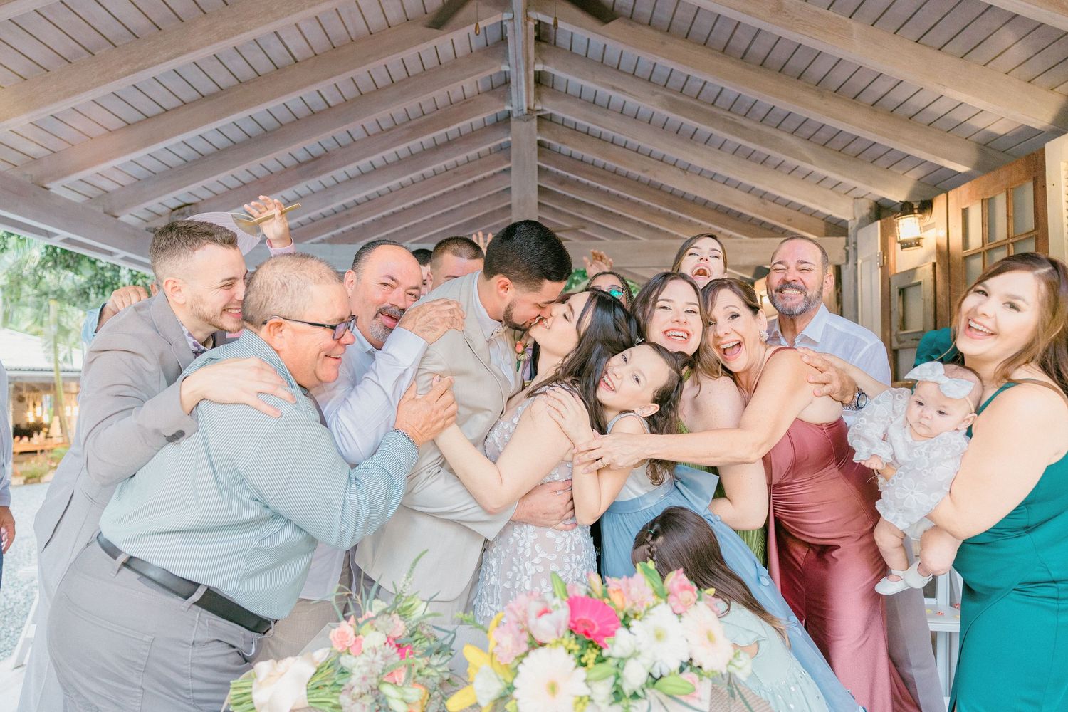 Wedding party gathered together for a fun group photo under a covered patio.