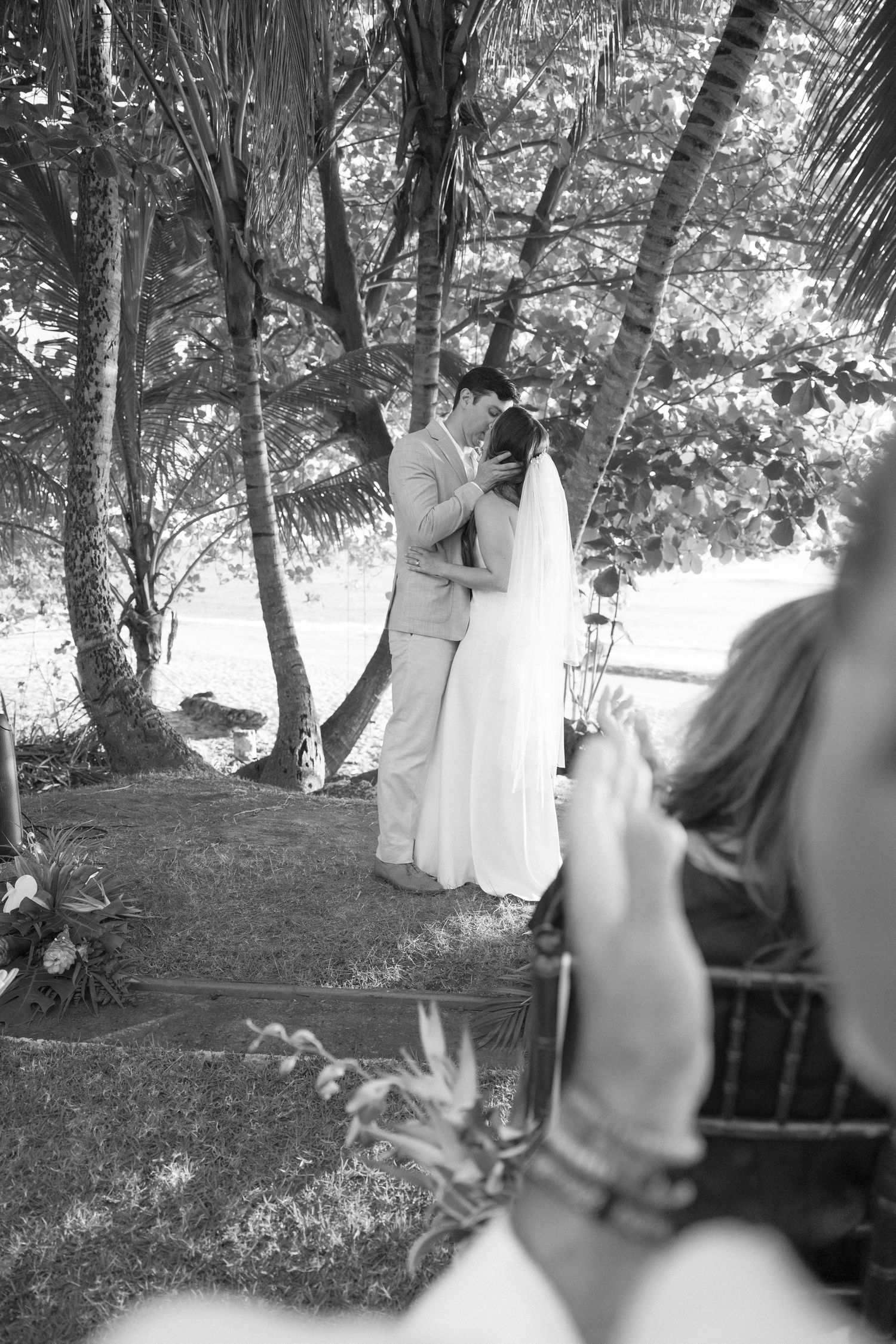 Black and white photo of outdoor wedding ceremony under shaded trees.