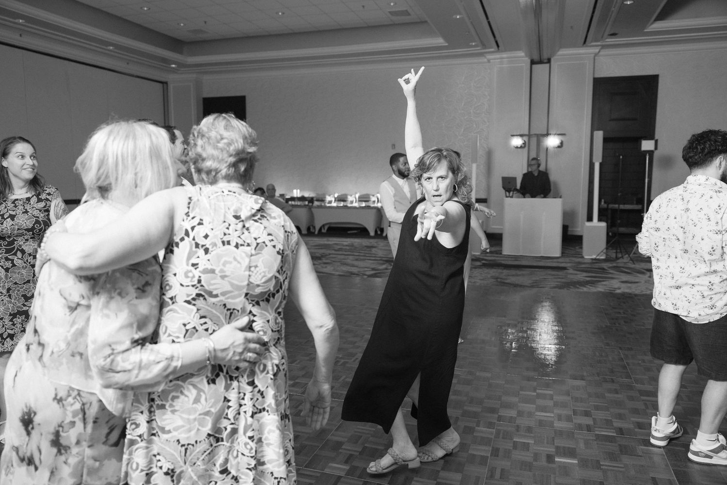 Wedding guests dancing and celebrating together on a ballroom dance floor at a reception.