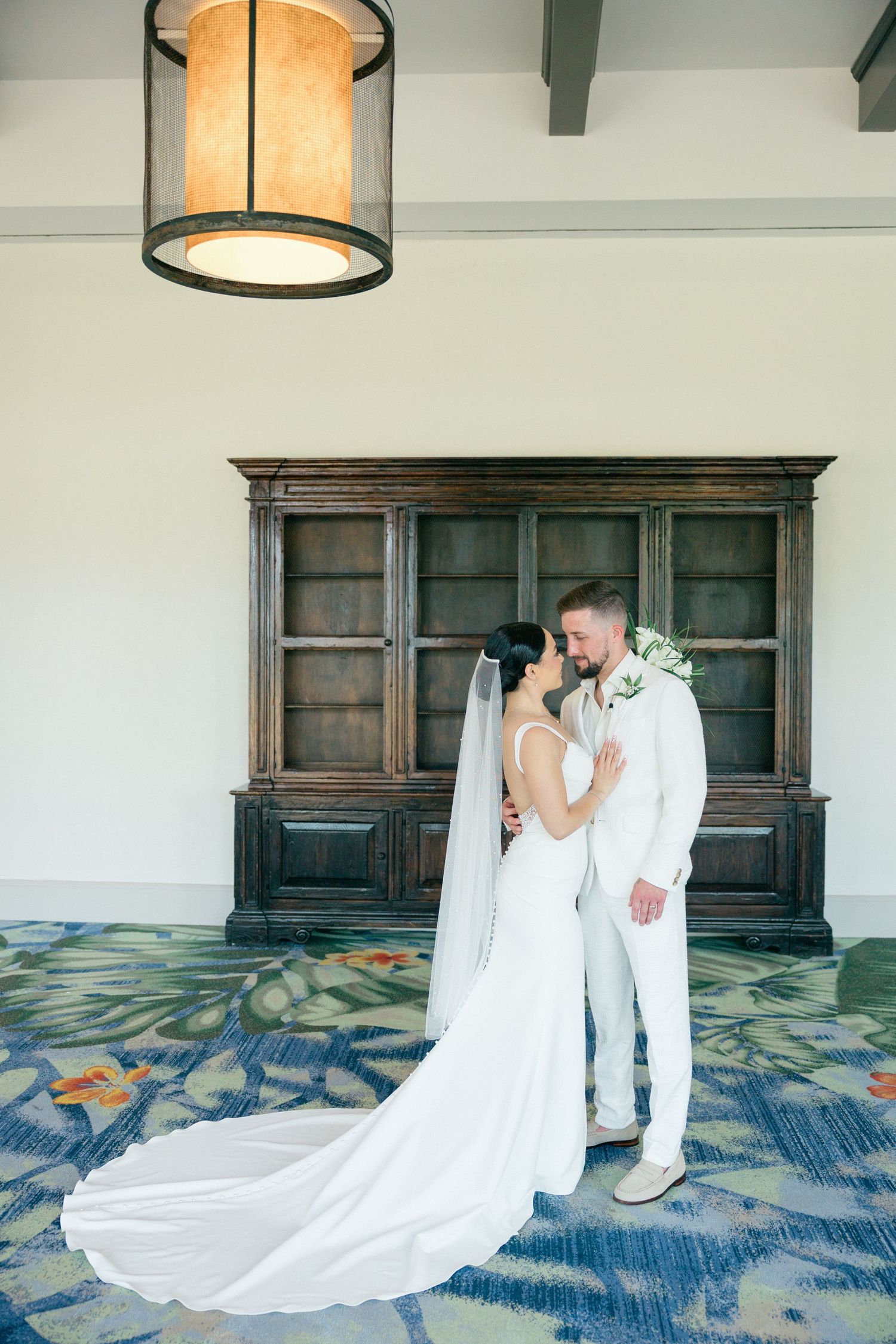 Romantic wedding portraits against white wall with dark wood paneling and blue patterned carpet.