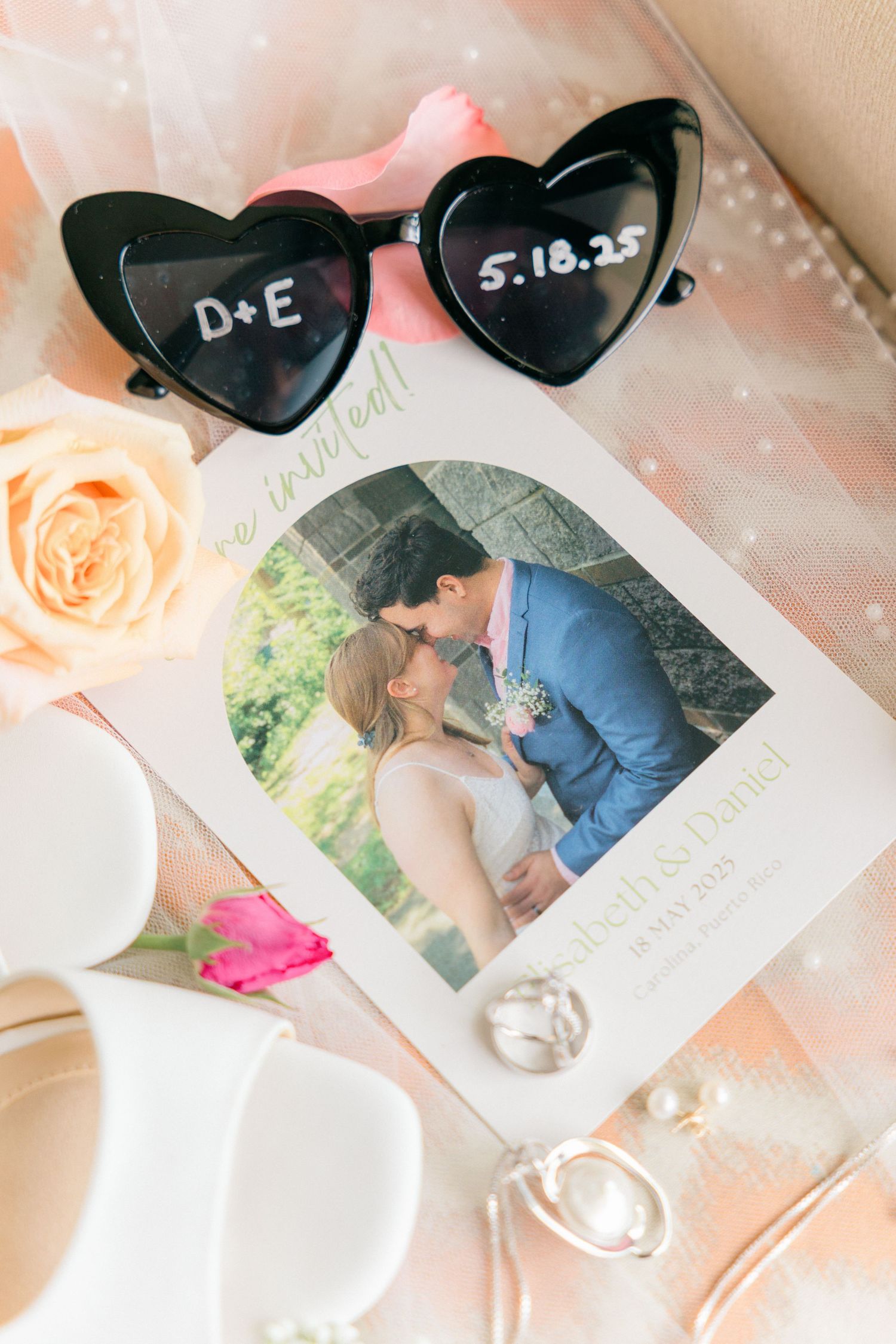 Wedding photos and heart-shaped sunglasses arranged with romantic decor.