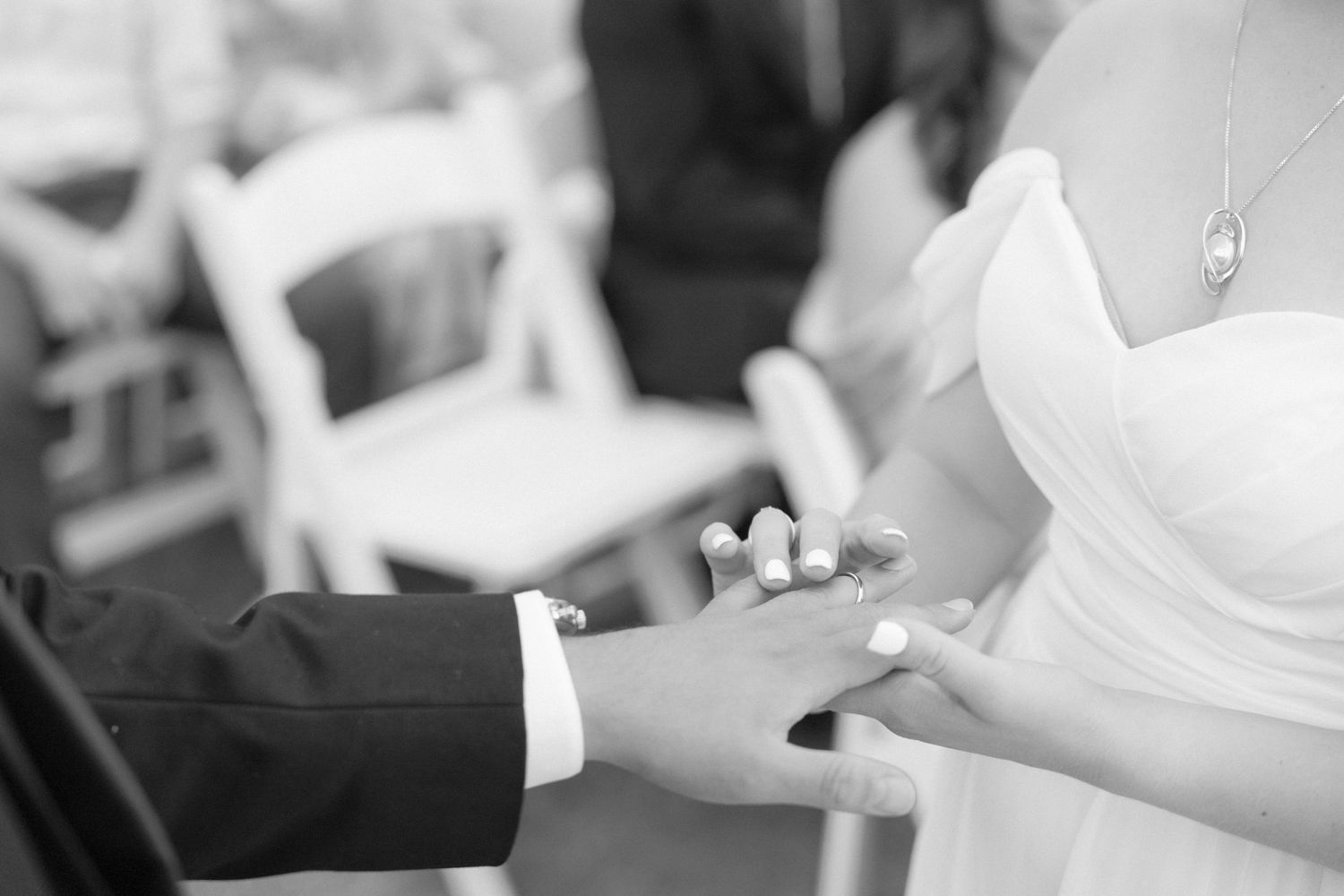 Black and white detail shots of wedding ring exchange between couple's hands.