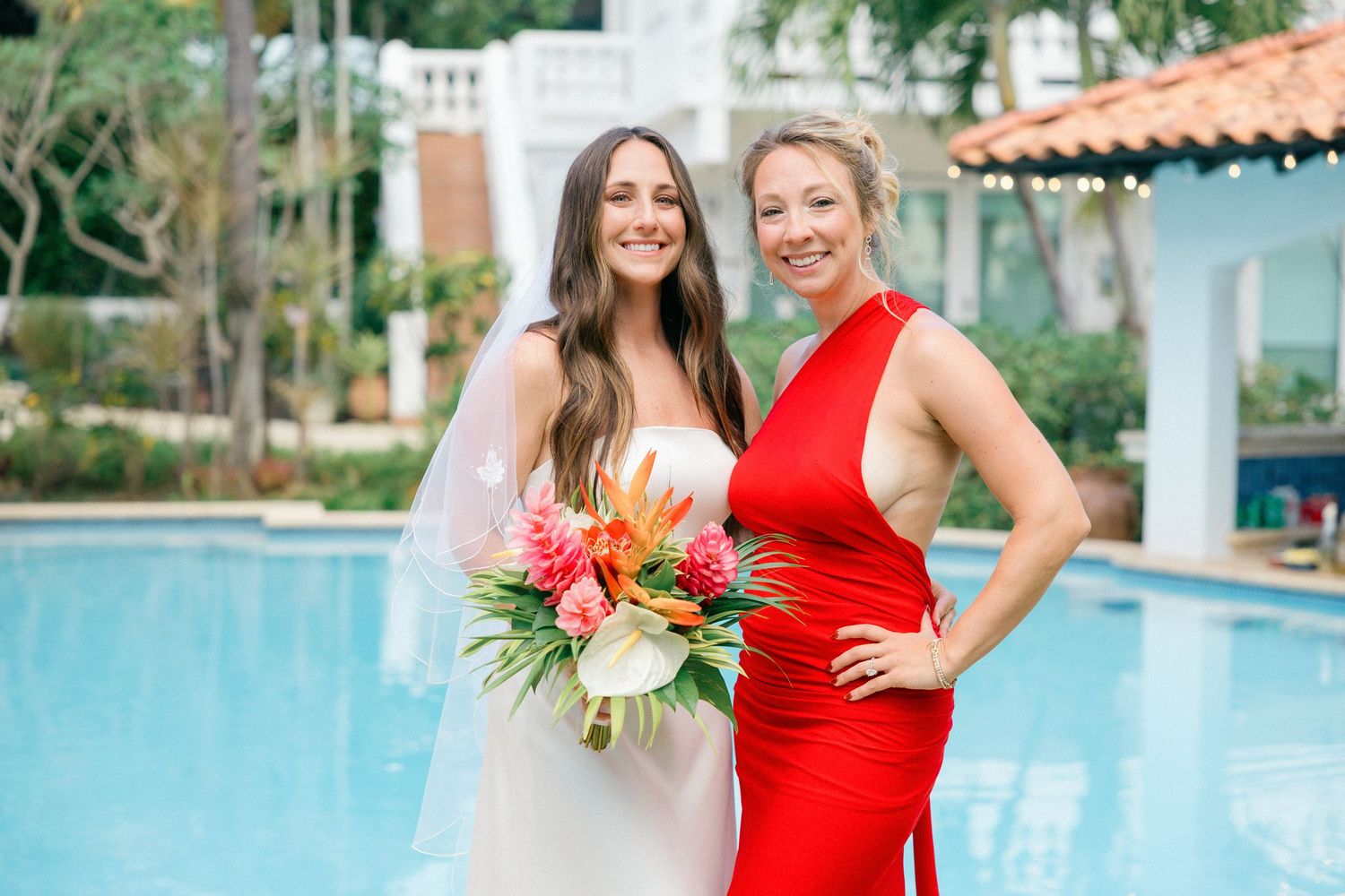 Wedding party members pose together near a swimming pool wearing coordinated formal attire.