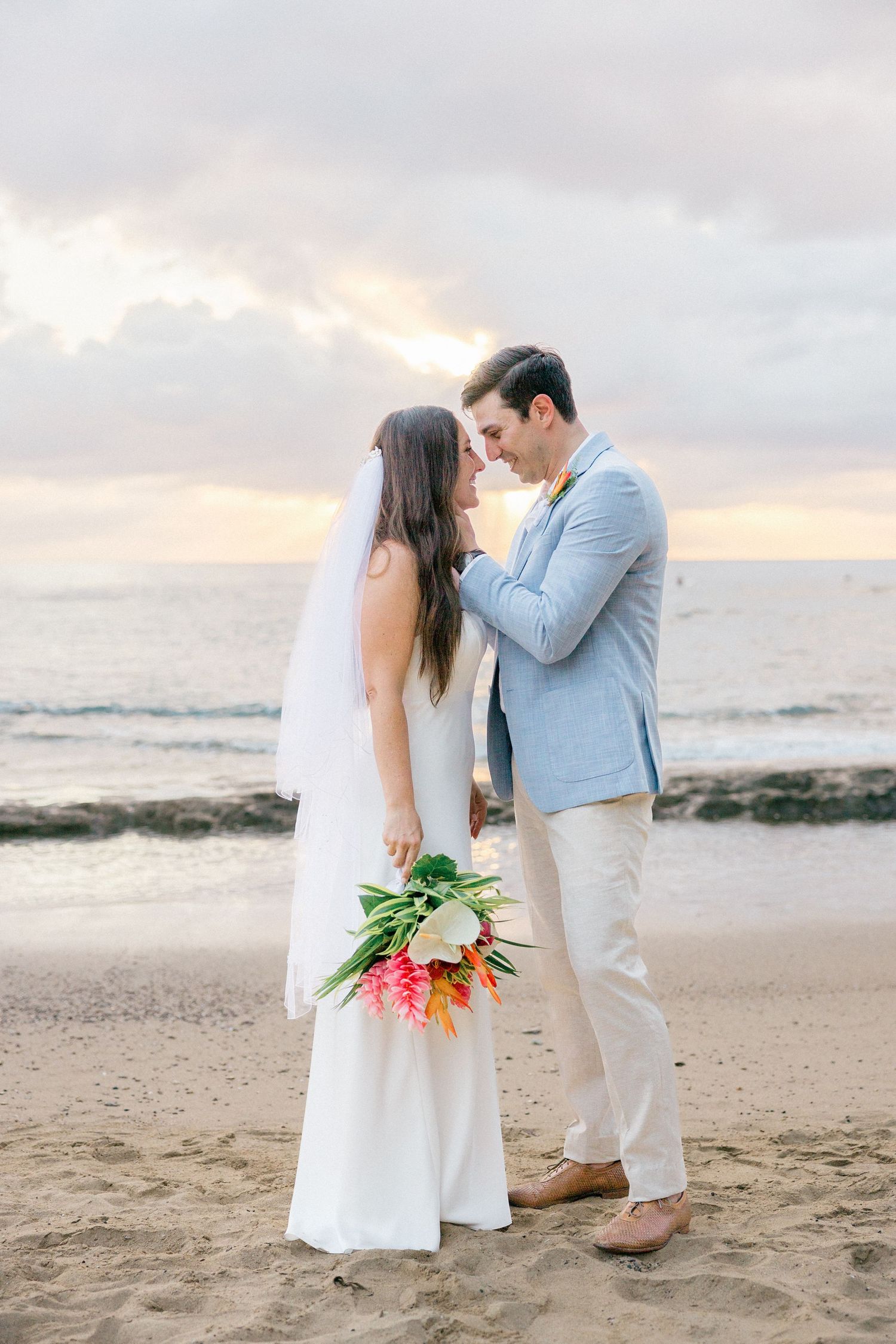 Romantic sunset beach wedding portraits with tropical bouquet.
